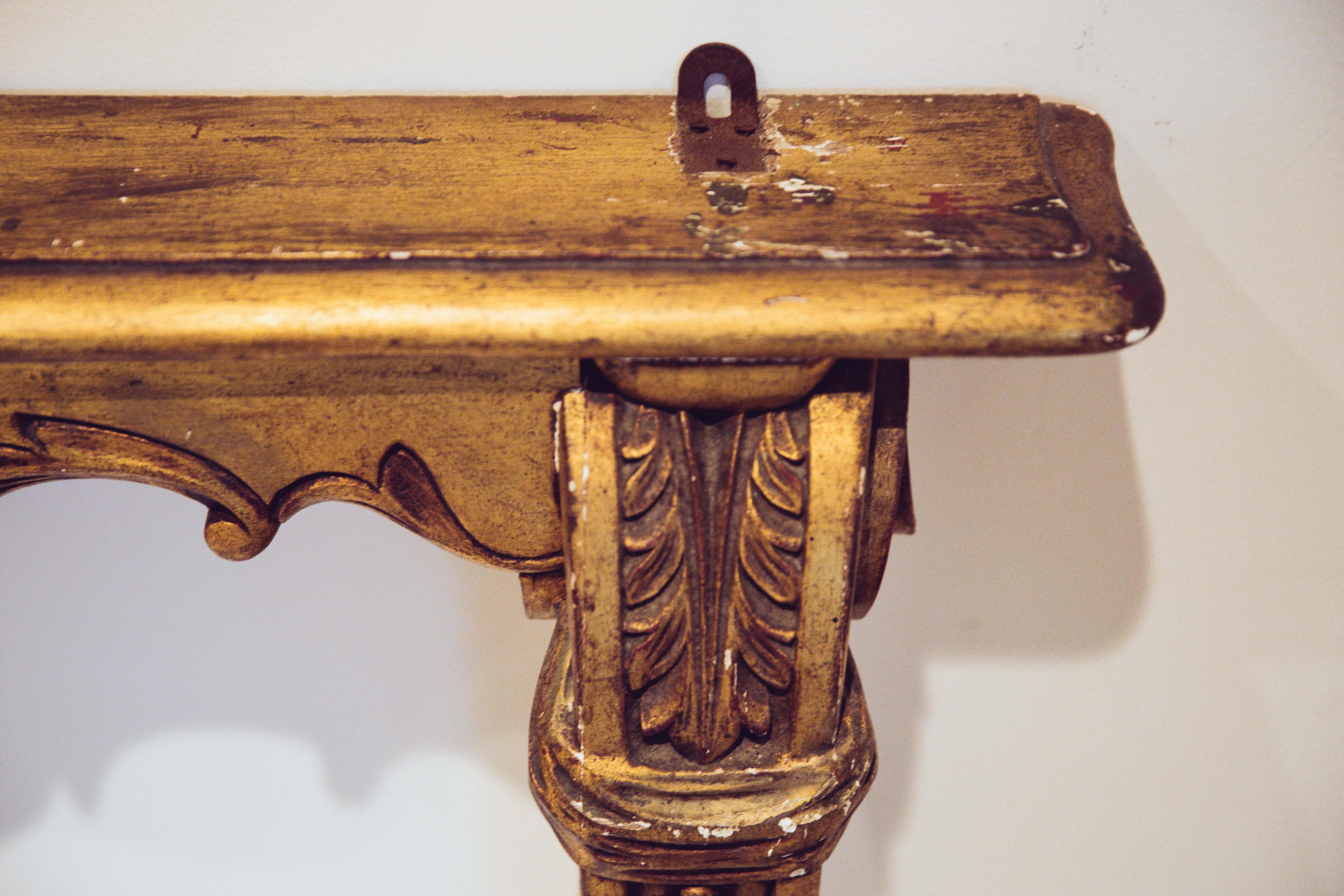 A 19th century small French Louis XVI style hand carved and gilt wooden, rose flowers, cartouche centered console table from the late 19th century.
The ensemble is raised on two angled tapering legs, accented with acanthus leaves in their upper