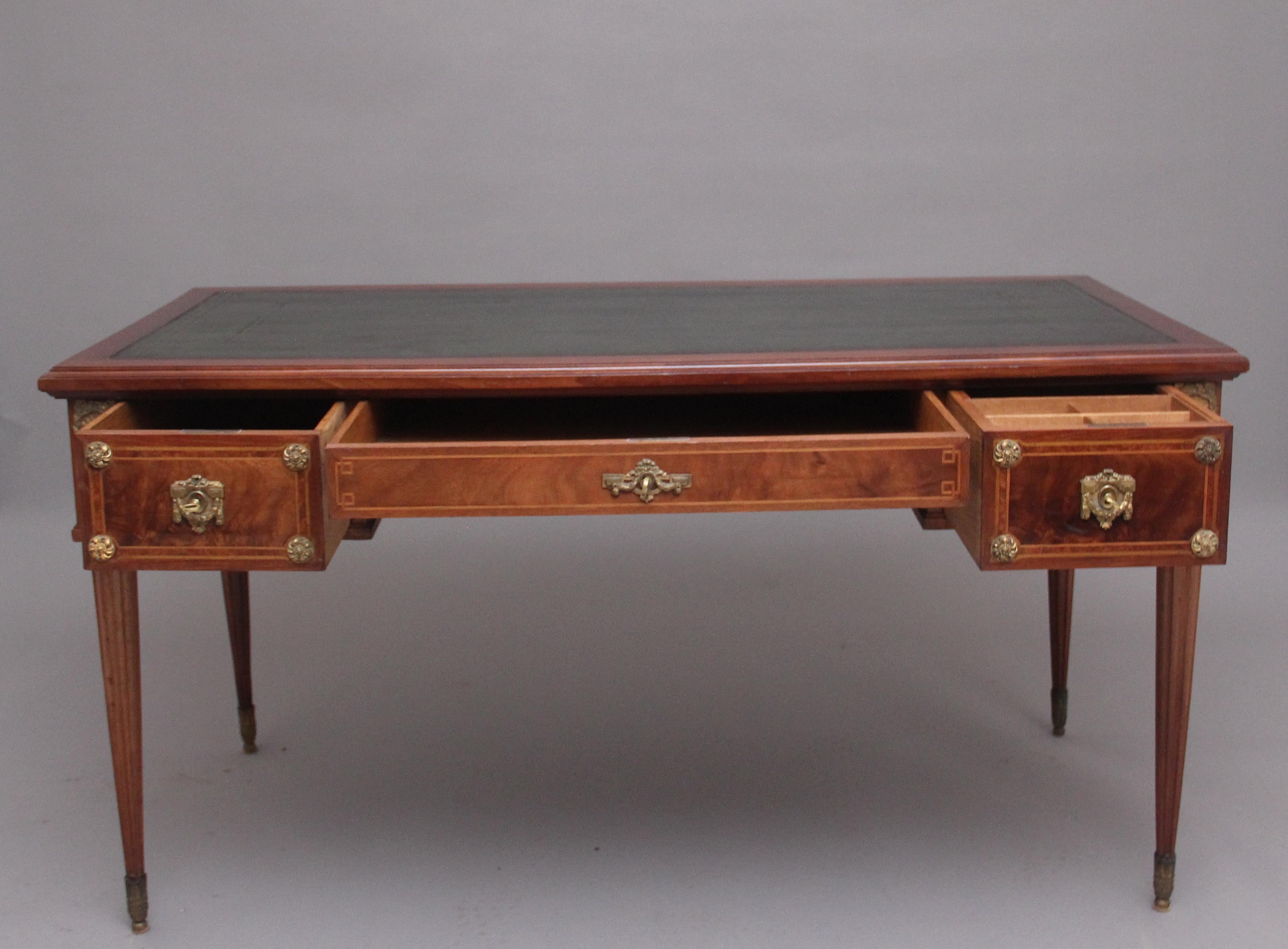 A freestanding 19th century French mahogany writing desk, the moulded edge top having a green leather writing surface decorated with blind and gilt tooling, the front of the desk consisting of three oak lined drawers with original decorative brass