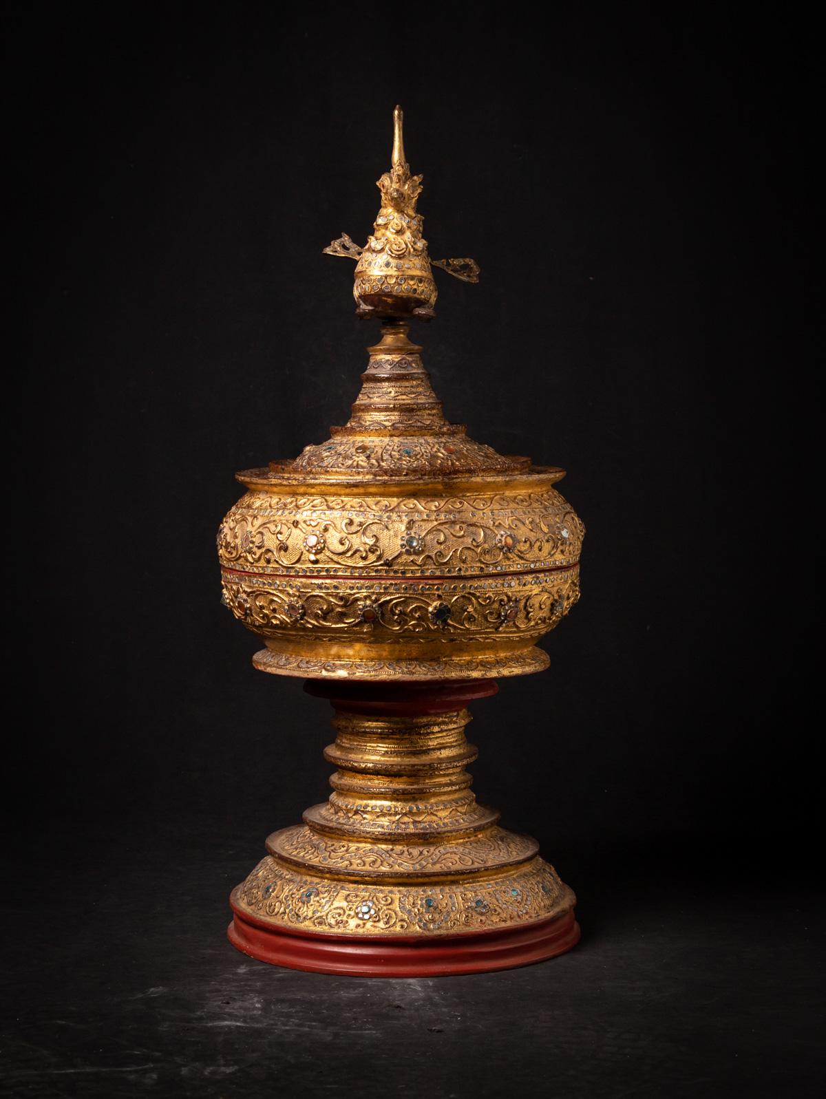 Ce vase d'offrande birman antique et doré est un chef-d'œuvre exquis du XIXe siècle de style Mandalay, fabriqué à partir de laque traditionnelle et richement doré à l'or fin (24 krt.). D'une hauteur de 79 cm et d'un diamètre de 35 cm, elle est ornée