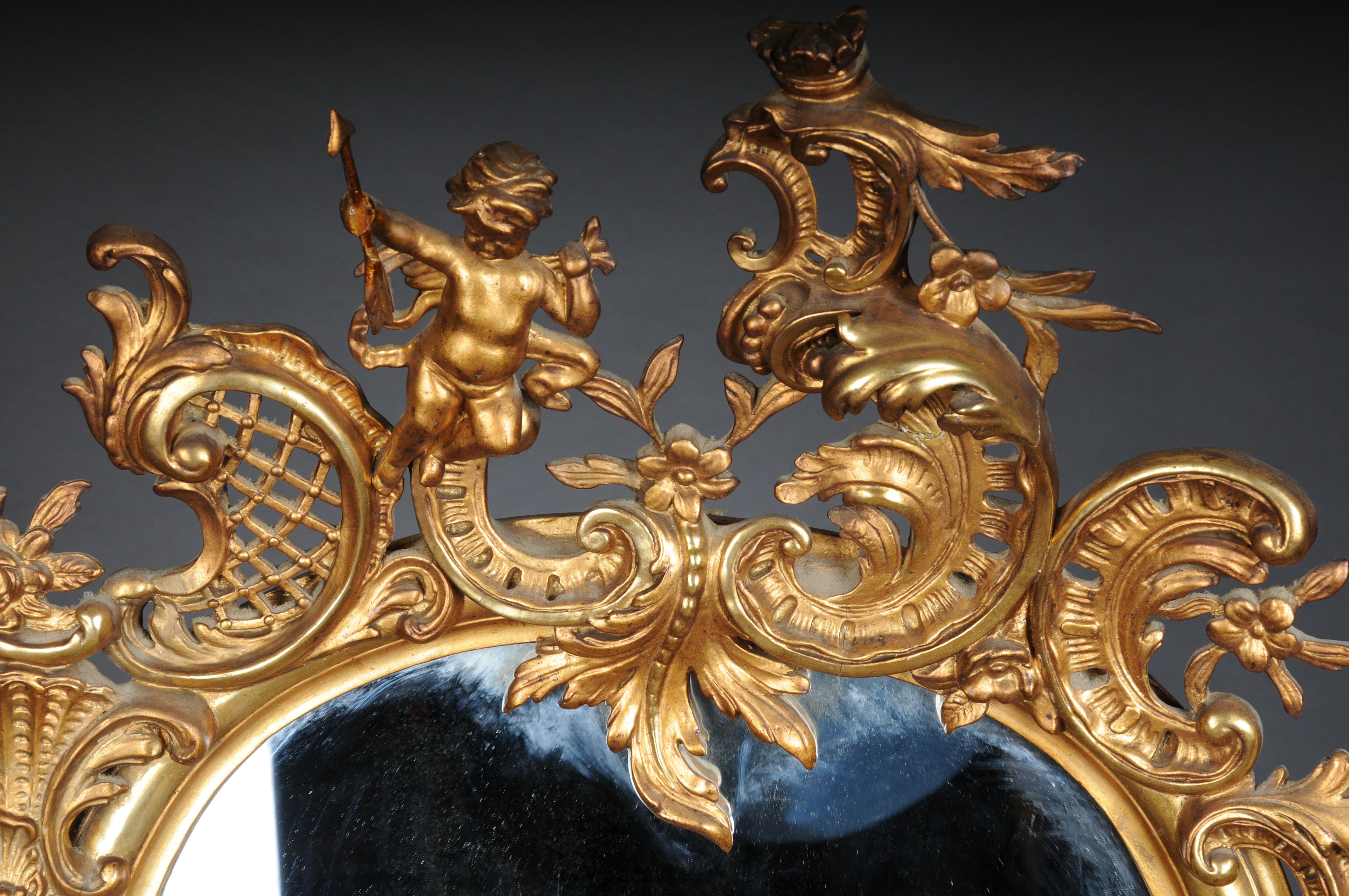 Antique gilded Rococo wall mirror

Rich ornate mirror frame, crowned with a diamond shield with putti.
