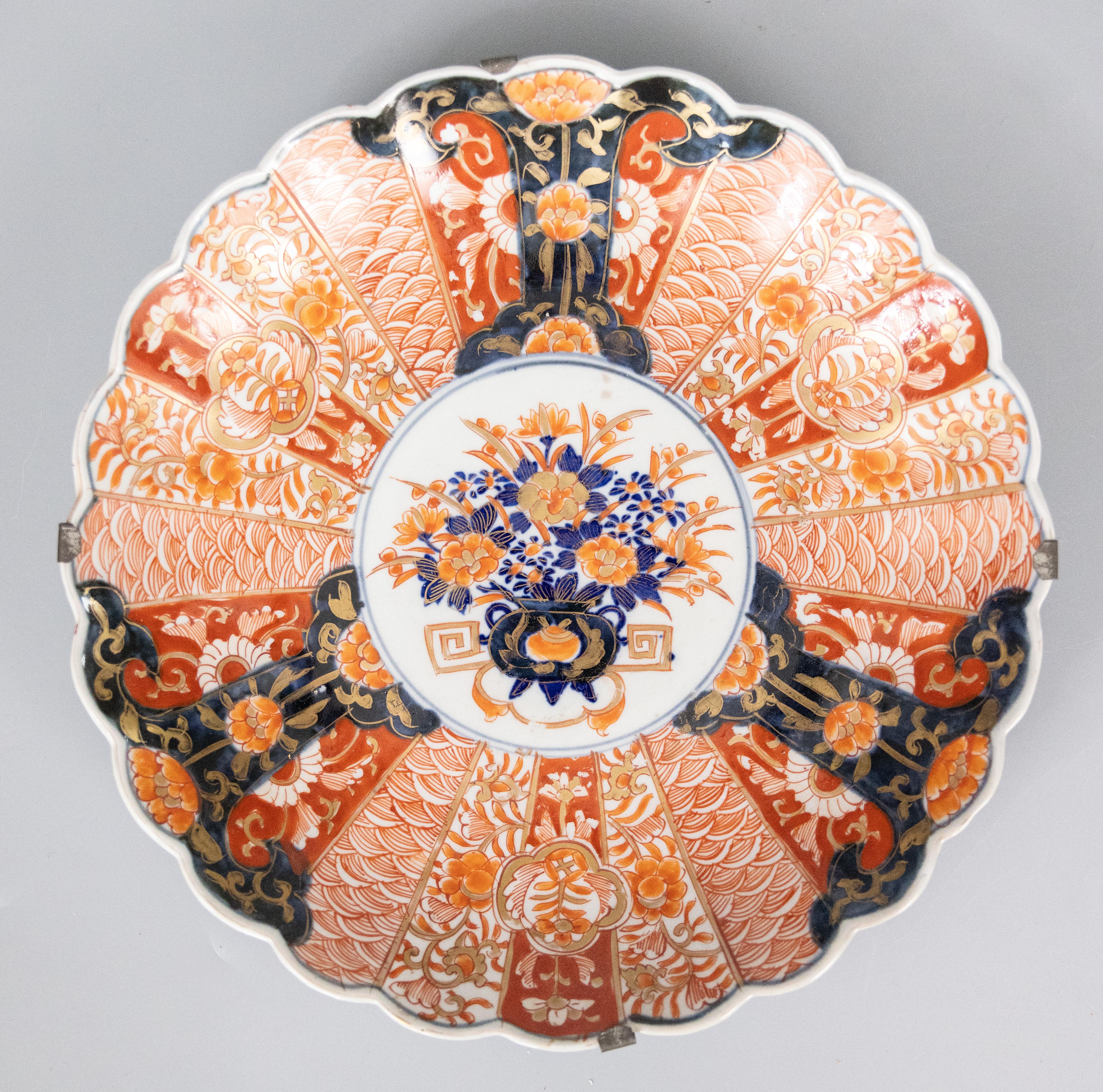 A wonderful pair of antique, 19th century Imari chargers with lovely lobed edges, in traditional vibrant oranges and blues. They retain the original antique hangers.