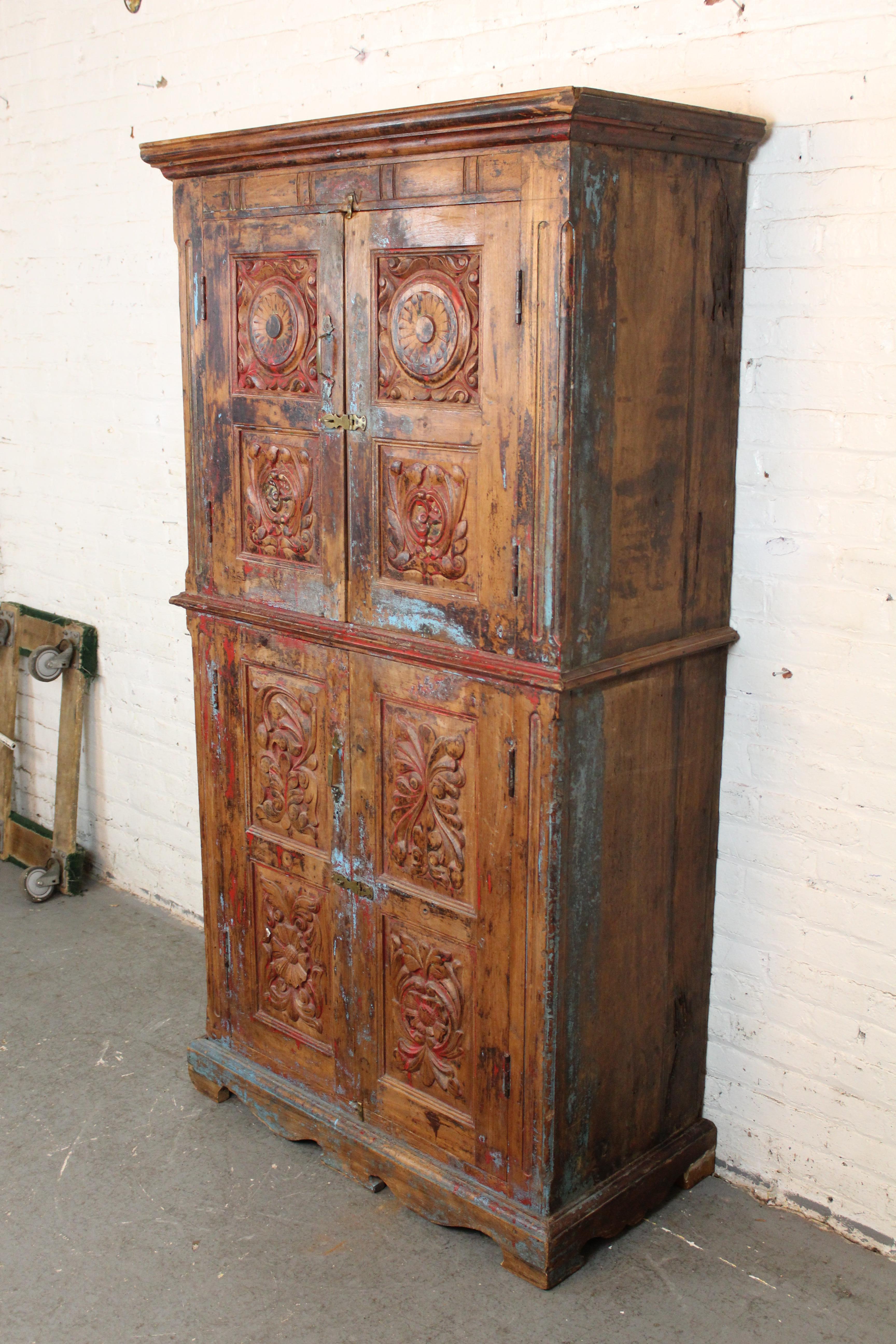 Add a big old-world touch to any space with this impressive antique Indian armoire. Dated to the late 19th century, this behemoth case piece has been intricately carved of solid teak wood, with doors featuring highly detailed floral and spinning