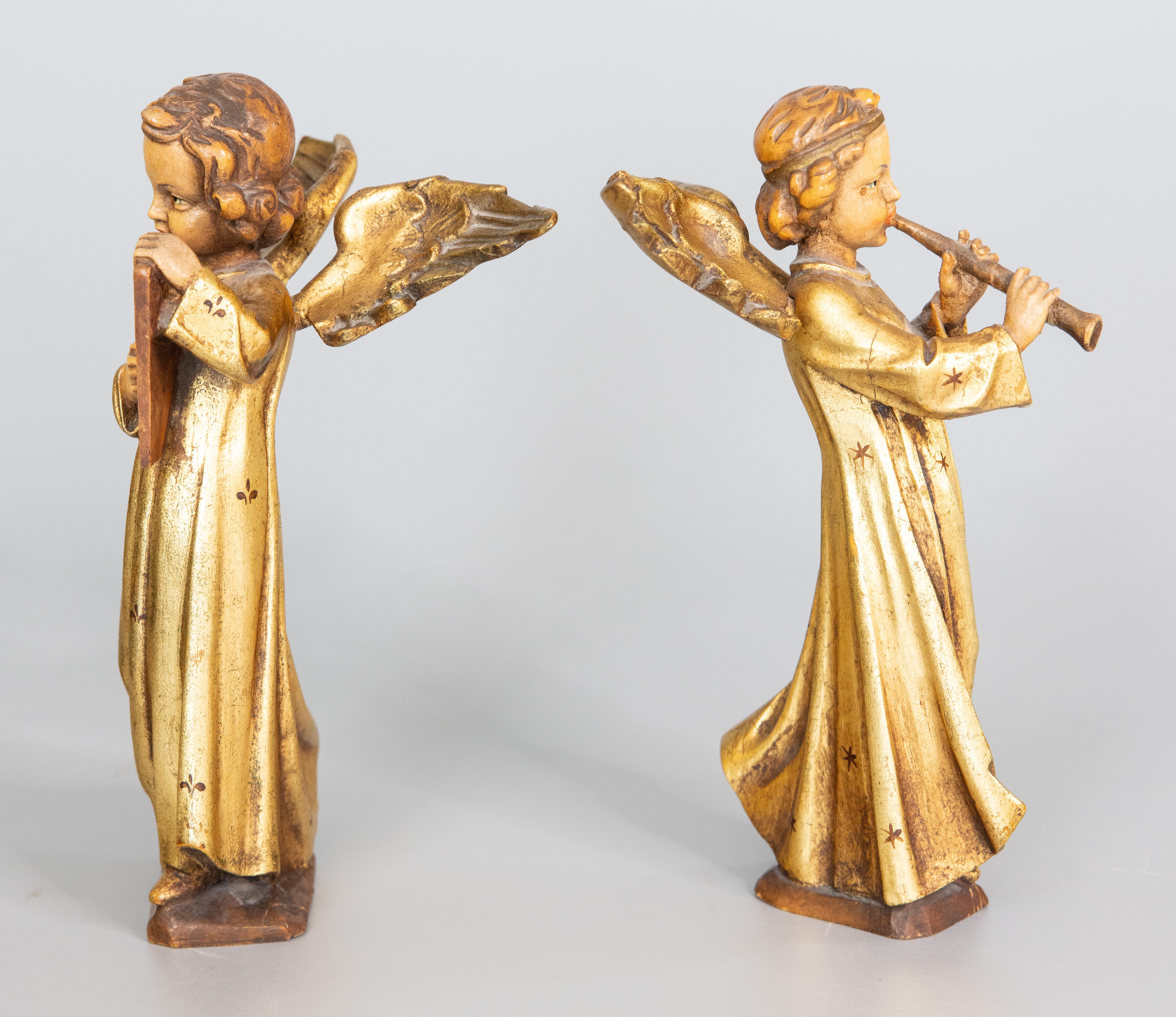 Ein Paar hübscher geschnitzter Holzfiguren, die zwei Engel mit Flöte und Harfe darstellen, vergoldet und mit kleinen Lilien verziert, stehen auf Sockeln.