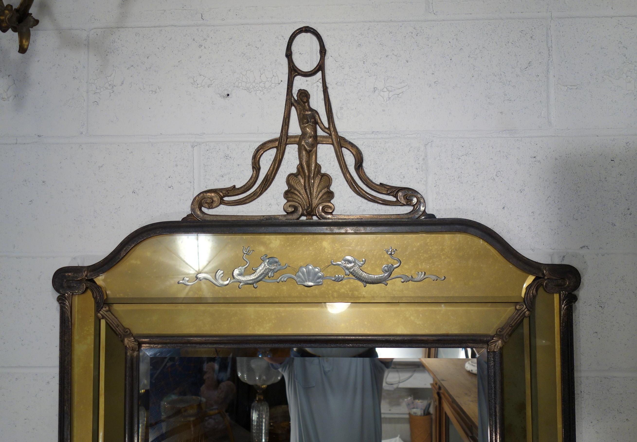A fine antique Italian Liberty style beveled mirror with golden burnished metal frame and details, facet glass over enamel, and engraving of Renaissance dolphins on top facet over silver metal. Lovely figural top metalwork piece (hinged and