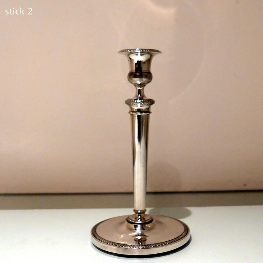 A stylish pair of early 19th century plain formed circular based candlesticks designed with fixed nozzles and decorated with lower fluting to the capital. The stem has additional snake skin strap work belt for decoration and the outer border of the