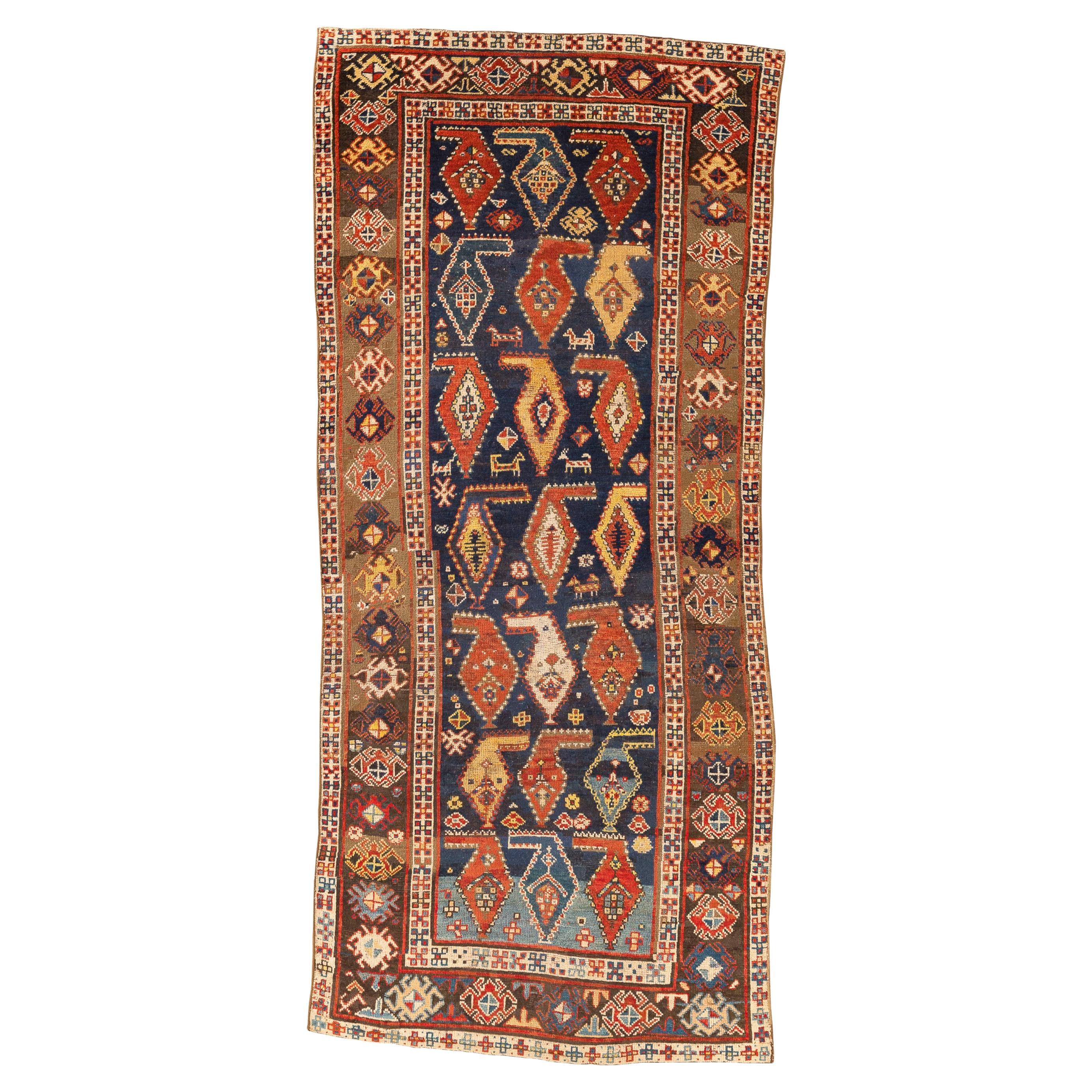 Karabagh - South Caucasus

This is an antique rug rich in geometric figures. The dark blue central field is dominated by three horizontal rows of botehs and seven vertical columns. The botehs are suspended from a horizontal strap at the top that