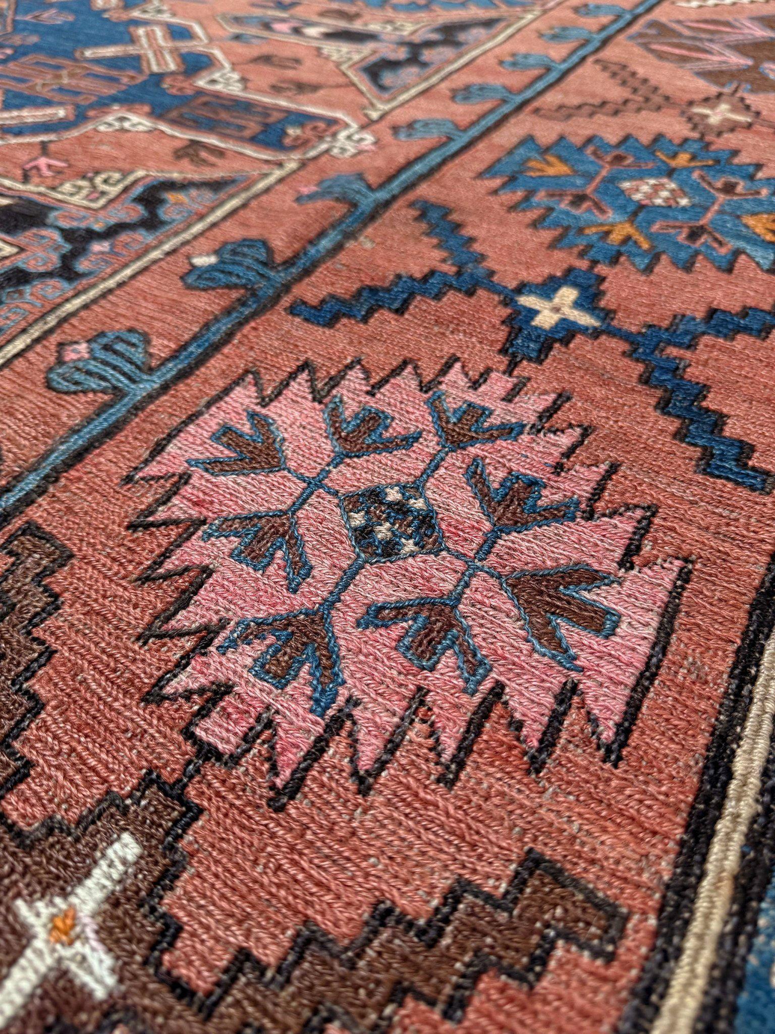 Questo tappeto Konagkend Soumak della fine del XIX secolo, proveniente dalla regione di Kuba, è un capolavoro di colore e geometria. L'iconico motivo a stella di Lesghi marcia su un campo rosso malva, mentre i toni dell'indaco di mezzanotte, del