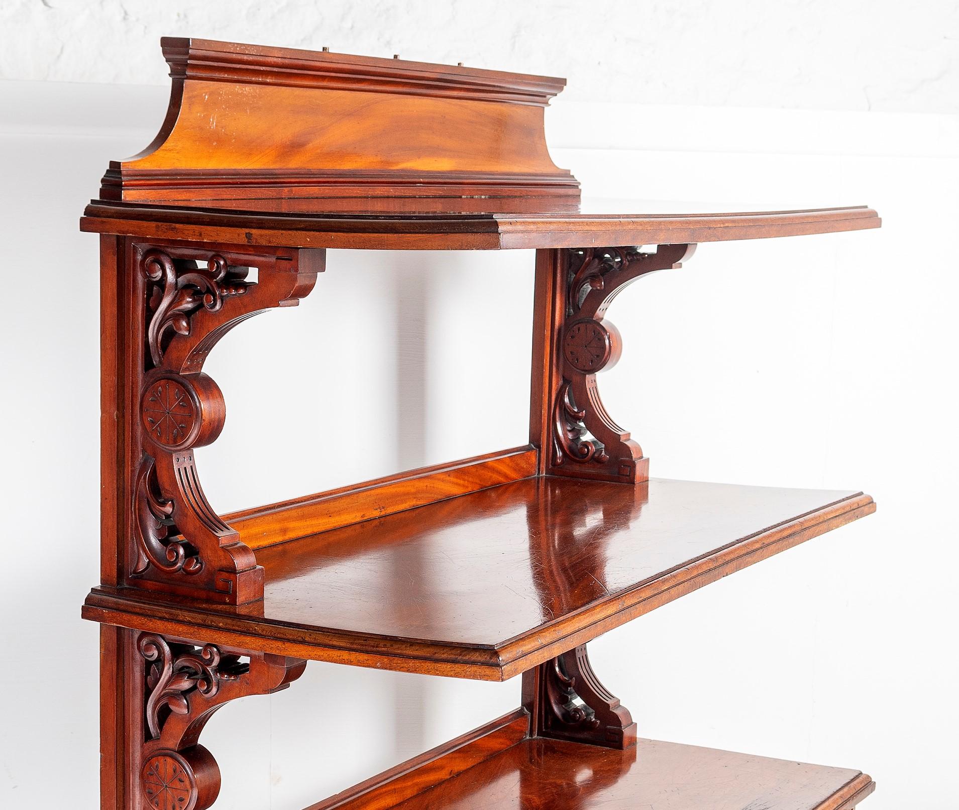 A Victorian Mahogany three tier Buffet Table, English circa. 1860, having three rectangular shelves supported on scroll carved brackets. The lower shelf fitted with two frieze drawers, all raised on inverted baluster legs with its original brown pot