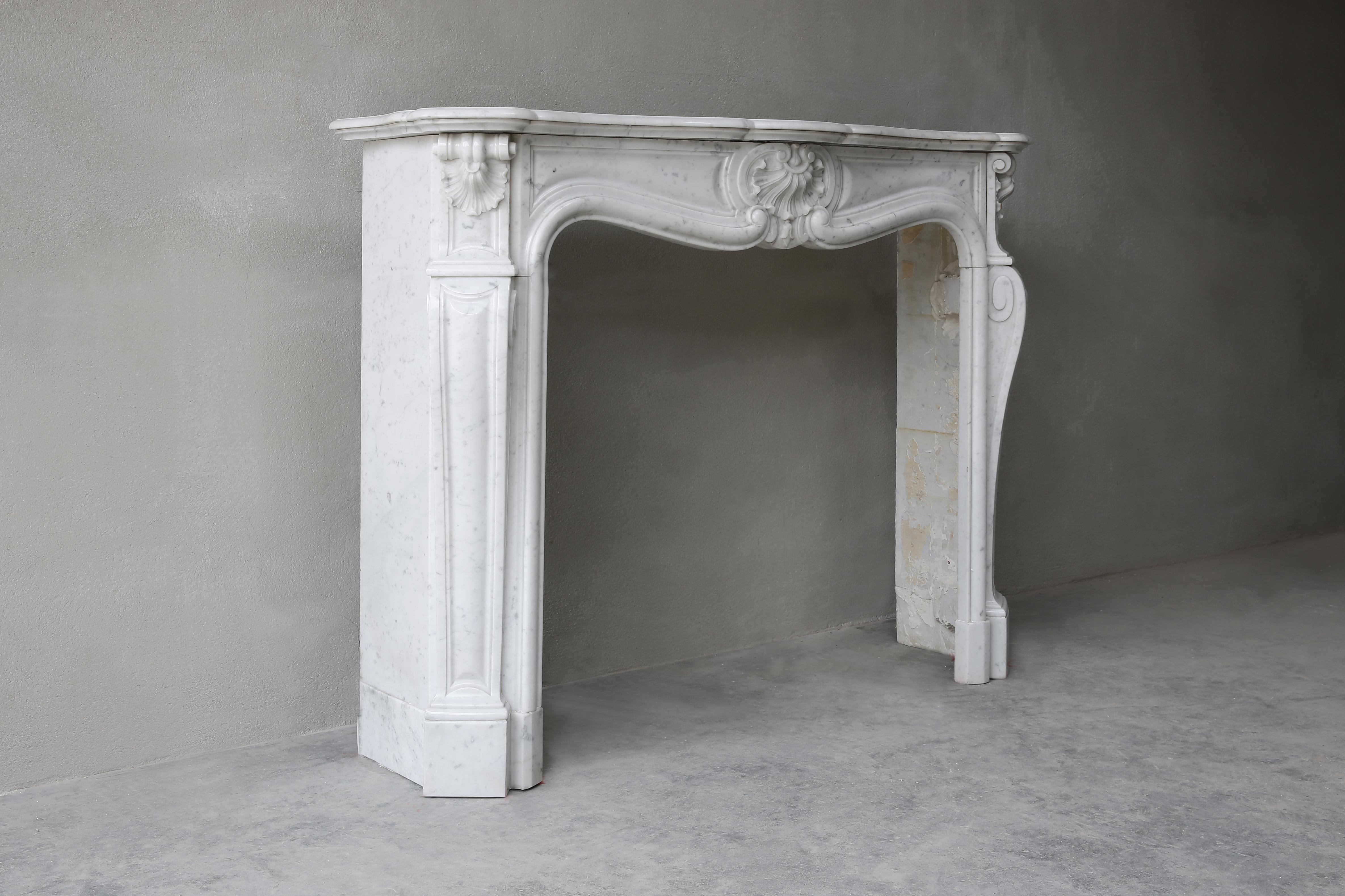Very nice compact fireplace made of Carrara marble. This antique mantel (fireplace) dates from the 19th century and is in Louis XV style. The mantelpiece is fitted with 'trois scallops' and has beautiful round shapes. The size of this antique