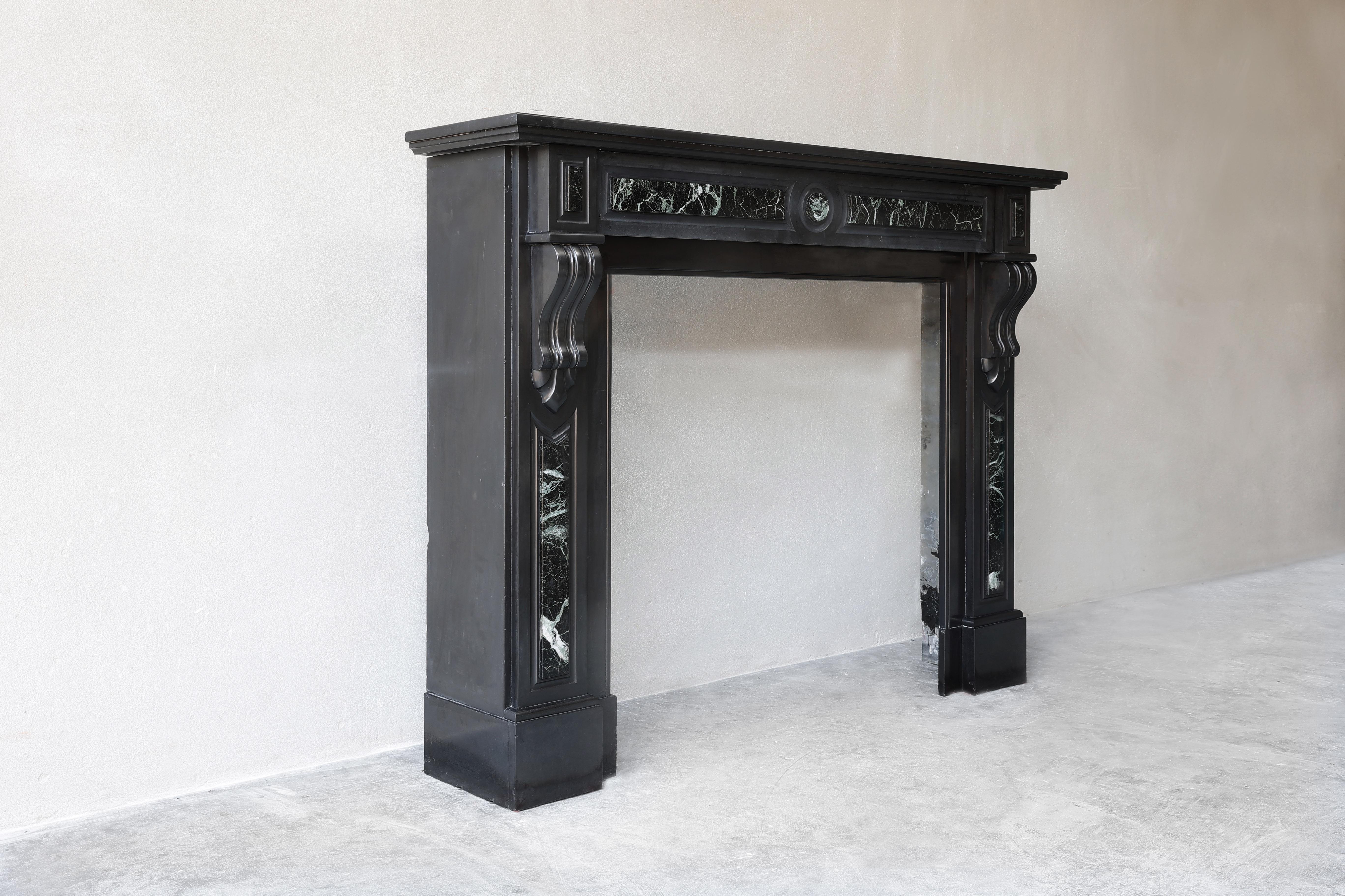 Beautiful ornate fireplace made of Noir de Mazy marble with green verde marble. A beautiful model in terms of size and shape. This fireplace is in Louis XVI style and dates from the 19th century. This type of fireplace fits perfectly in both a