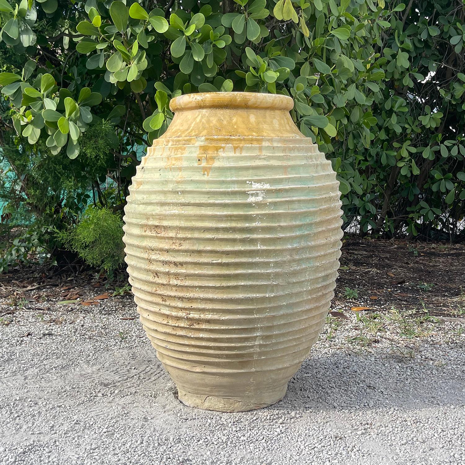 Ancienne jarre à huile d'olive grecque du Péloponnèse, dont le corps rond est orné d'un décor nervuré typique de Nekuma, réalisé à la main. Le bord est recouvert d'une glaçure jaune chaude. Ces récipients anciens en poterie de jardin étaient souvent