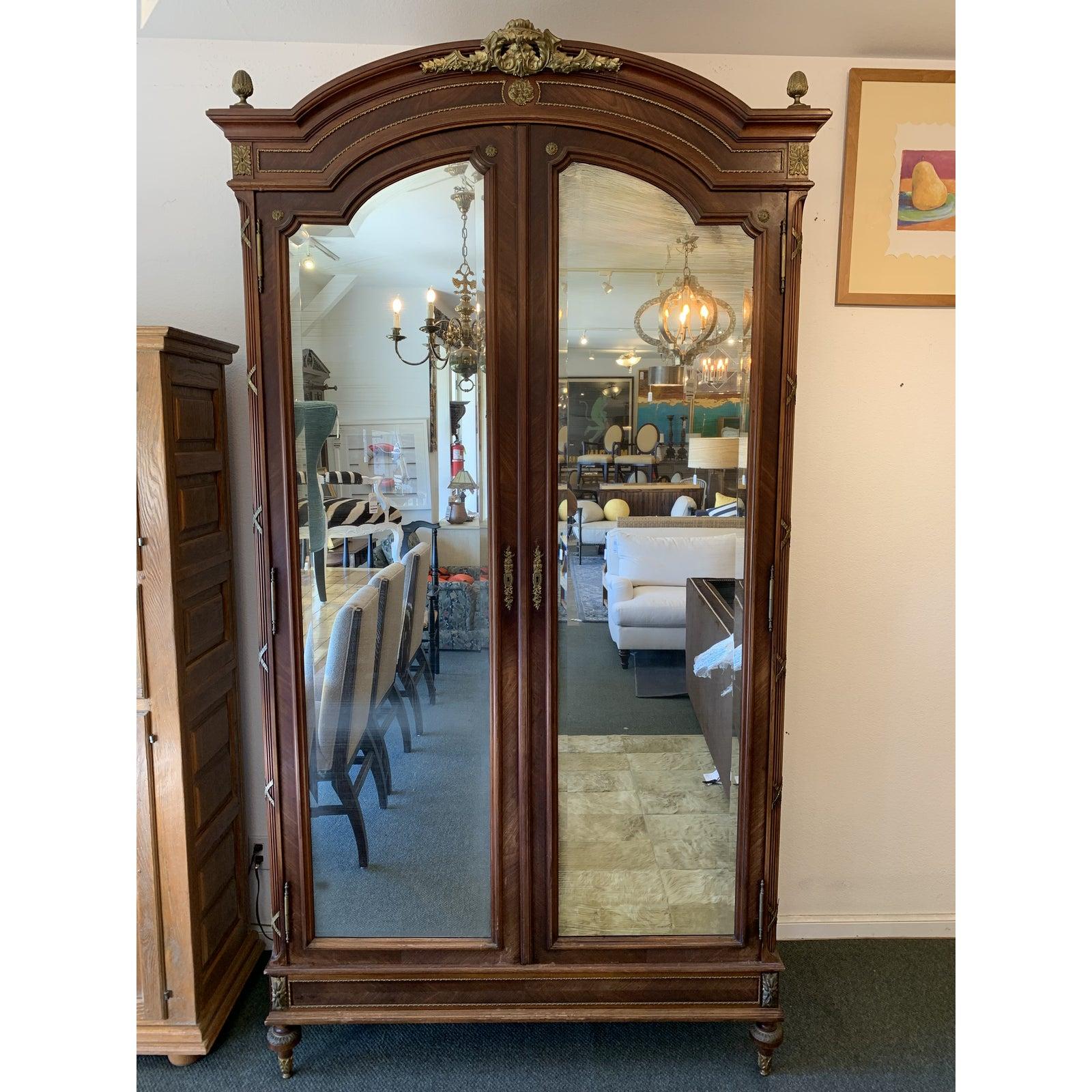 Design Plus Gallery presents a stunning Antique French Armoire. The French armoire is 19th Century mahogany-Louis XVI style with antiqued beveled mirror doors. The inside has beautiful shelves and several drawers that are finished with the same