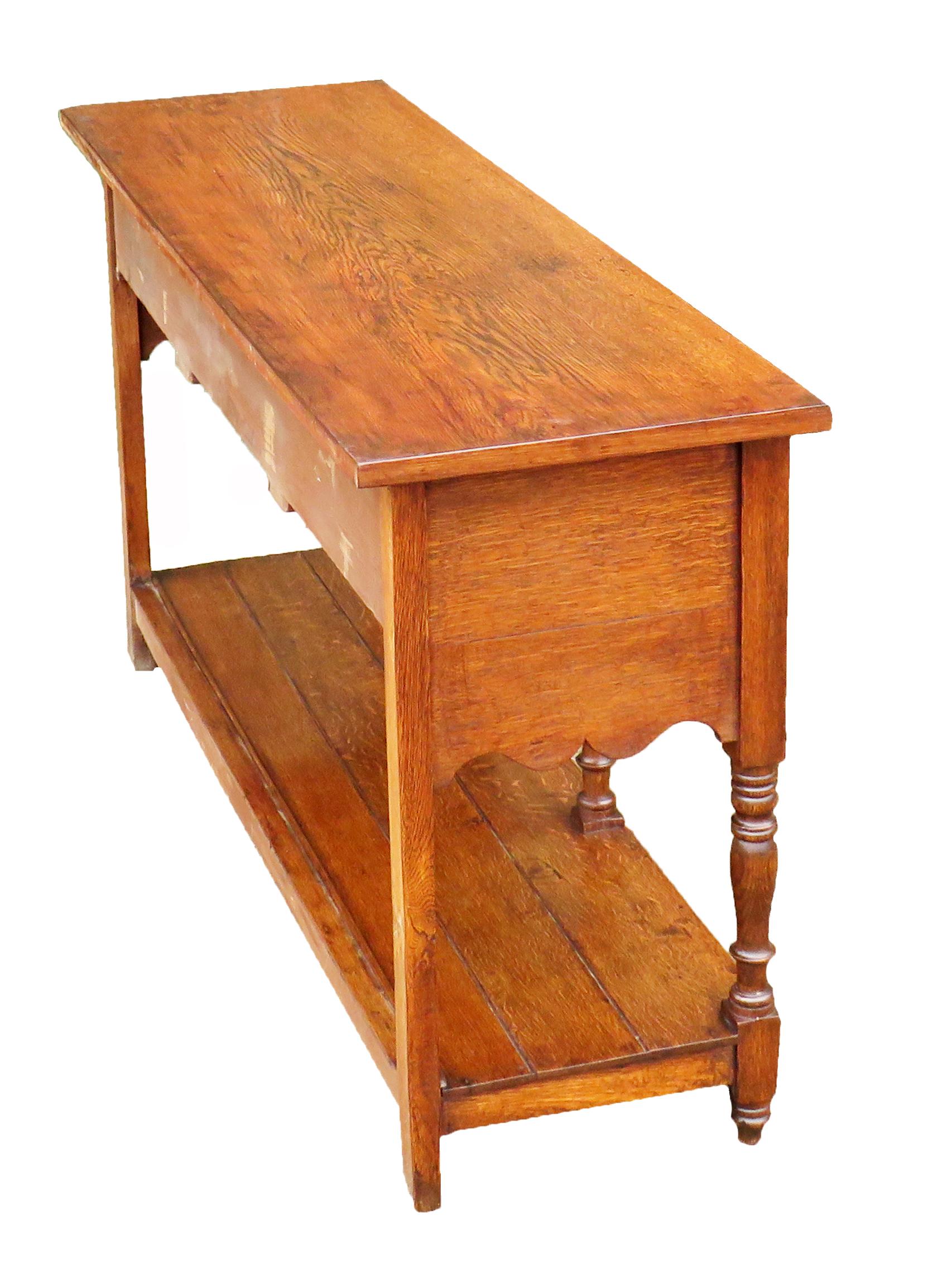 An attractive mid-19th century oak dresser base
Of good proportions having well figured top over
Three frieze drawers with later brass handles and
Elegant shaped apron raised on turned upright
With original pot board shelf below

(A very
