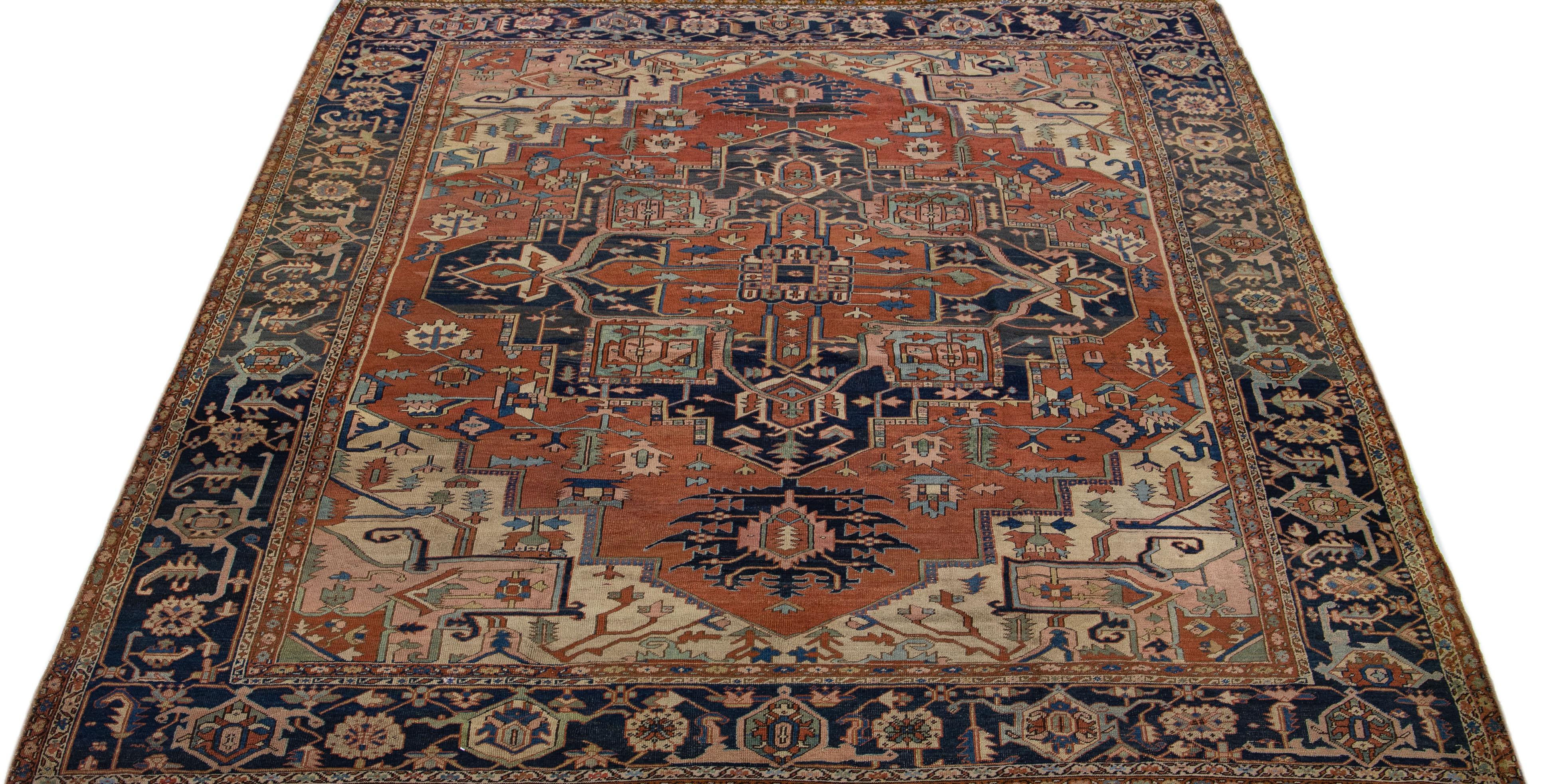 Beautiful antique Heriz hand-knotted wool rug with a rust color field. This Persian rug has a dark-blue designed frame with multicolor accents in a gorgeous medallion floral motif.

This rug measures: 10'3