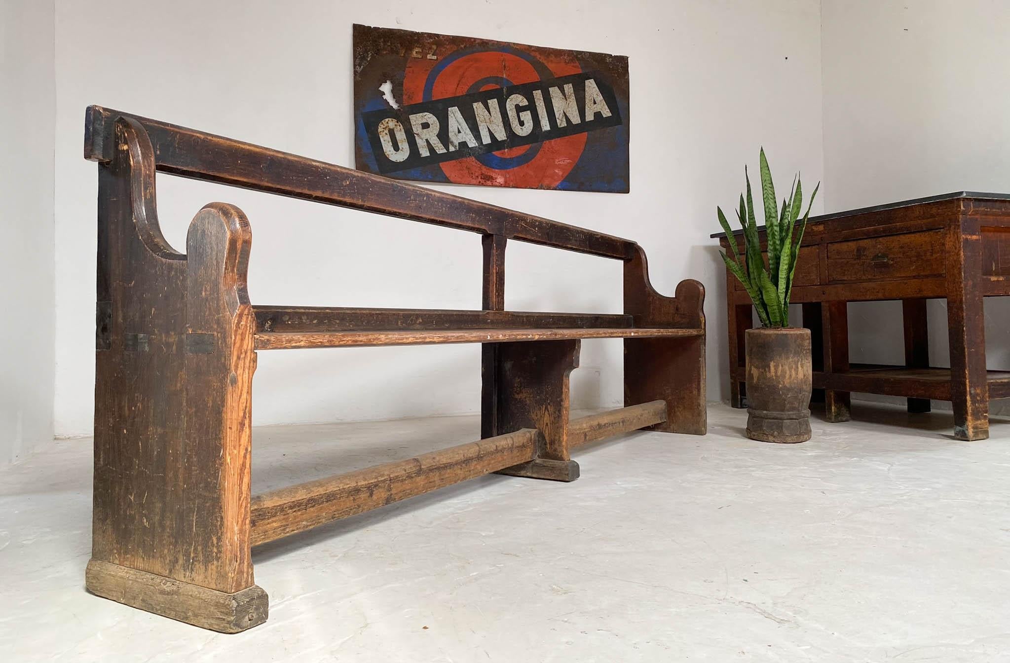 A lovely and unusual example of a pine church pew dating from the early 1800s. It is perfectly proportioned with curved ends and a simple bar in the center of the back. The stretcher below has wear created by the many people who have rubbed their