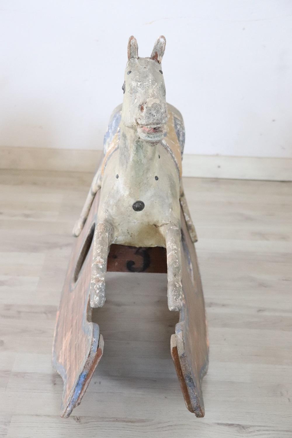 Beautiful antique rocking horse made in Italy at the end of the 19th century. The horse is made of wood and the body is covered in papier-mâché. Completely hand painted. Signs of wear missing tail and bridle. A collectible toy.