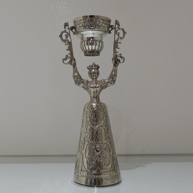 A stylish late 19th century figural German silver wager/marriage cup decorated with an ornate lower bell dress (bowl) and an upper “swivel” bowl. The decoration on the wager cup is beautifully set on a matt background for creative contrast.

