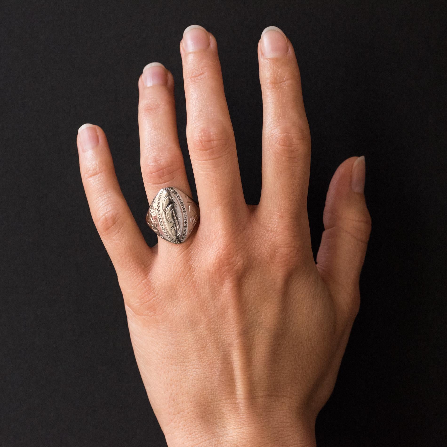 Ring in silver.
The top of this signet ring is shuttle-shaped, the center is decorated with the initials GC surrounded by a beaded. On both sides, the start of the ring is chiseled with a plant motif. The carving is slightly weathered.
Height: 21