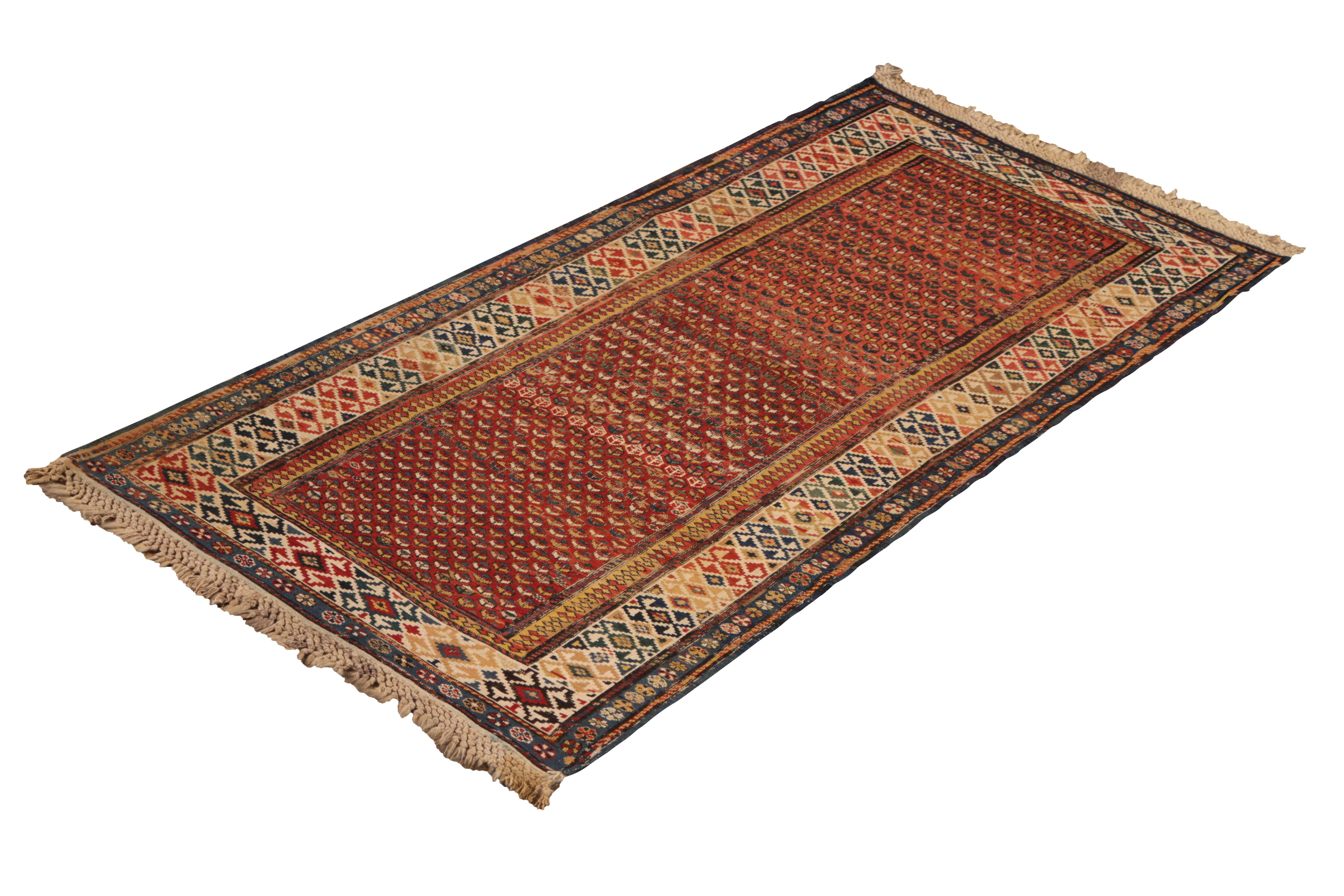 Hand knotted in wool originating from Russia circa 1890-1900, this antique rug connotes a 19th-Century Soumak design with a warm, traditional play of near-autumnal burn red and beige hues complemented by accenting, vibrant gold-yellow, blue, and