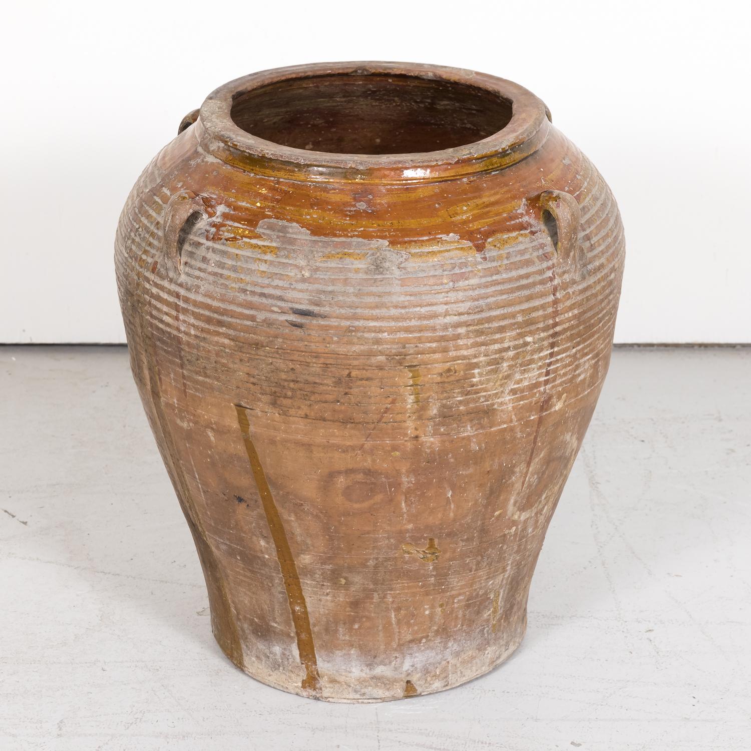 A 19th century traditional antique Spanish terracotta orza or olive jar handmade in the province of Tarragona in Catalonia, circa 1890s, having four handles and an unglazed exterior with circular striations with the neck, rim, and interior glazed a