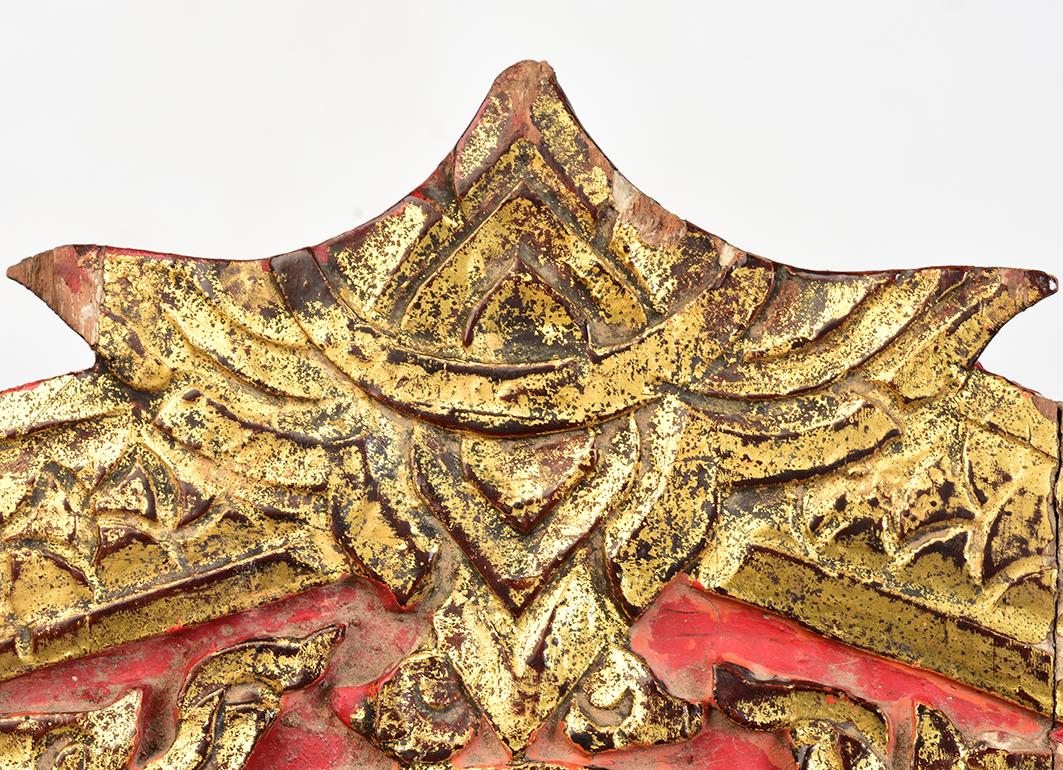 Thai wood carving, carved as Naga under leaf-shape, painted with lacquer and golden color, decorated with mirror-tiles, used for temple decoration.

The middle is carved as Dharmacakra surrounded by flowers and leaves. Dharmacakra (eight-sided