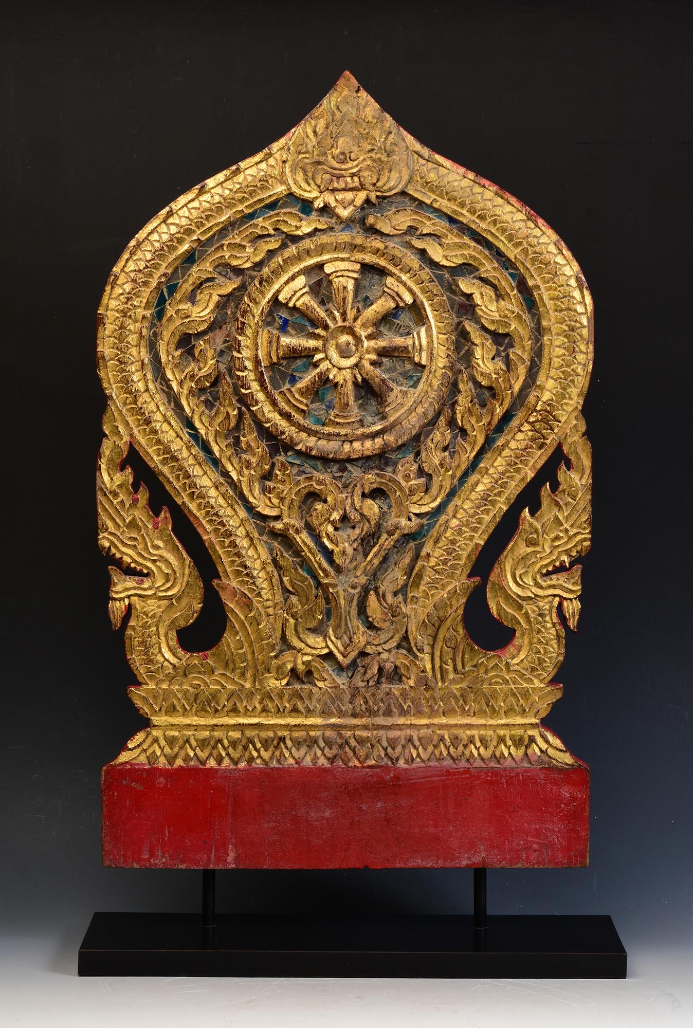 Thai wood carving, carved as Naga under leaf-shape, painted with lacquer and golden color, decorated with mirror-tiles, used for temple decoration.

The middle is carved as Dharmacakra surrounded by flowers and leaves. Dharmacakra (eight-sided