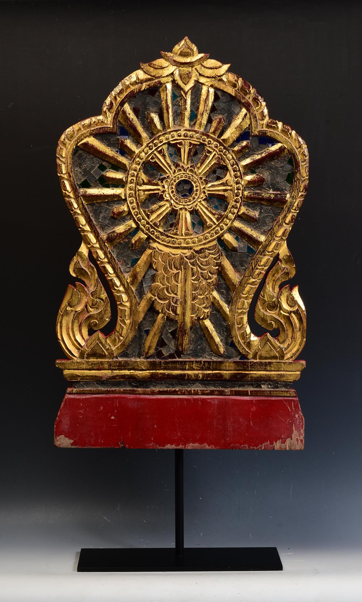 Thai wood carving, carved as Naga under leaf-shape, painted with lacquer and golden color, decorated with mirror-tiles, used for temple decoration.

The middle is carved as Dharmacakra surrounded by flowers and leaves. Dharmacakra (eight-sided