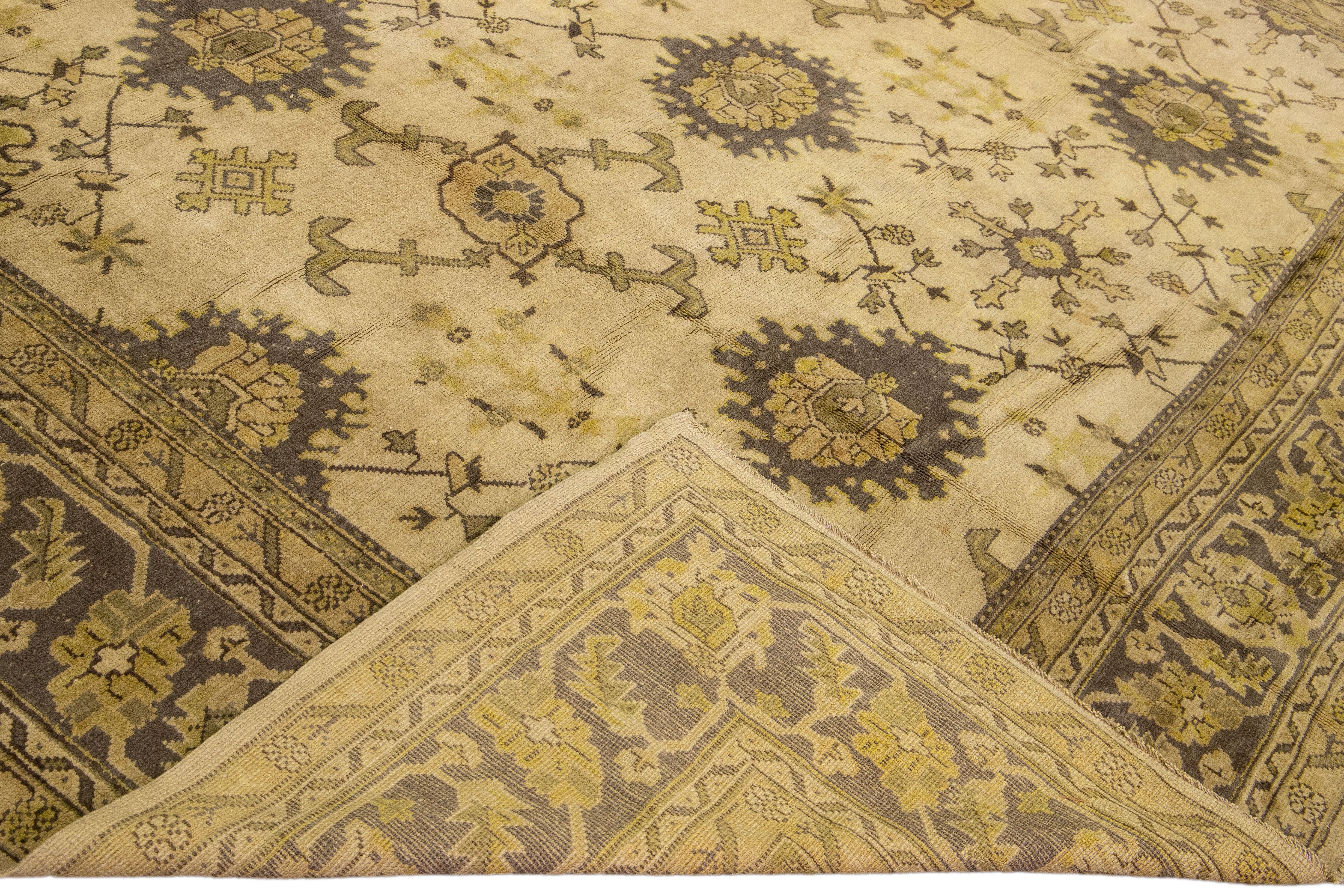 Beautiful Antique oversize Oushak hand-knotted Turkish wool rug with a beige/tan field. This Oushak has a yellow and gray accent in a gorgeous all-over geometric floral design.

This rug measures: 12'2