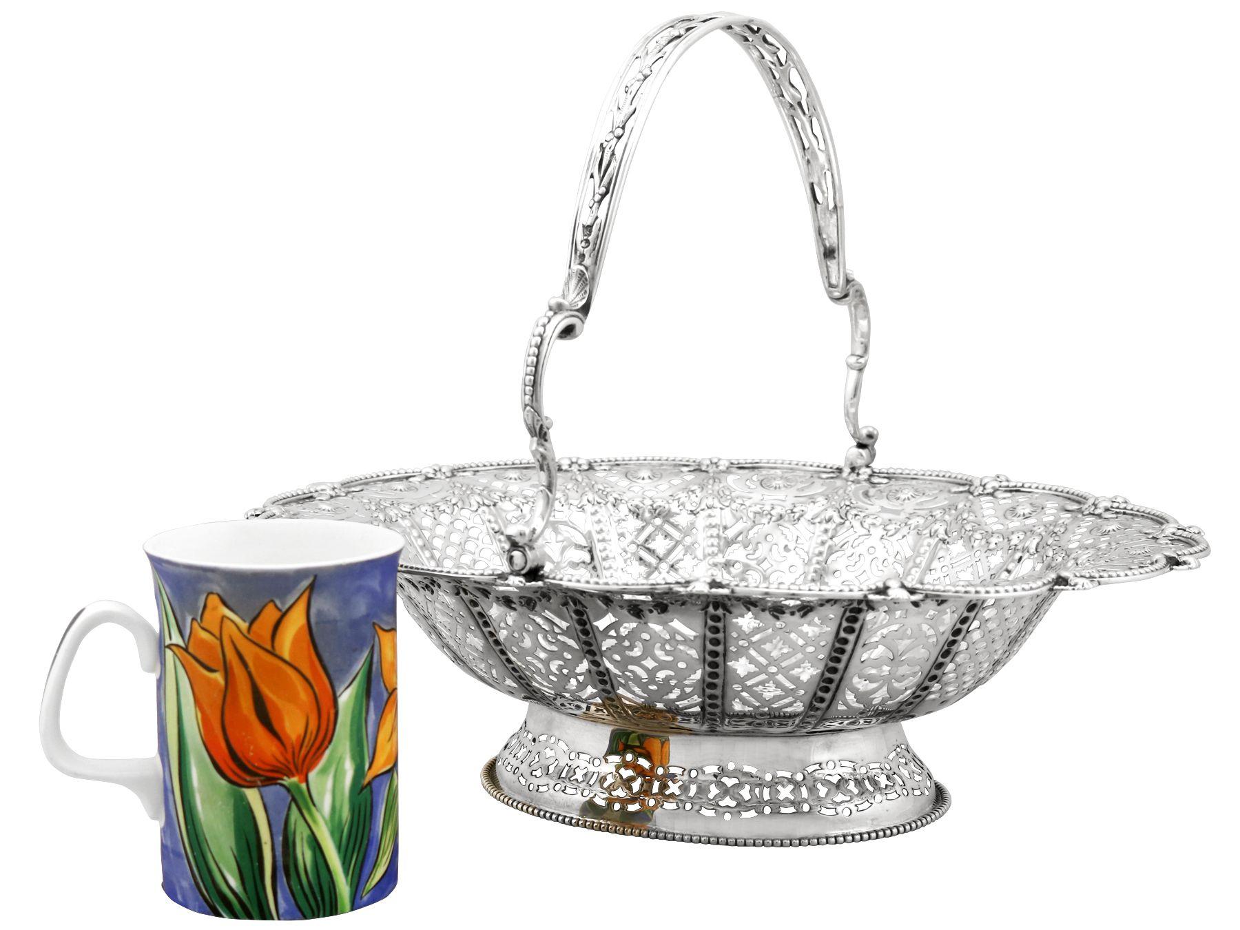 A fine and impressive antique Victorian English sterling silver swing handled cake basket; an addition to our ornamental silverware collection

This fine antique Victorian sterling silver cake basket has an oval rounded form onto a domed oval