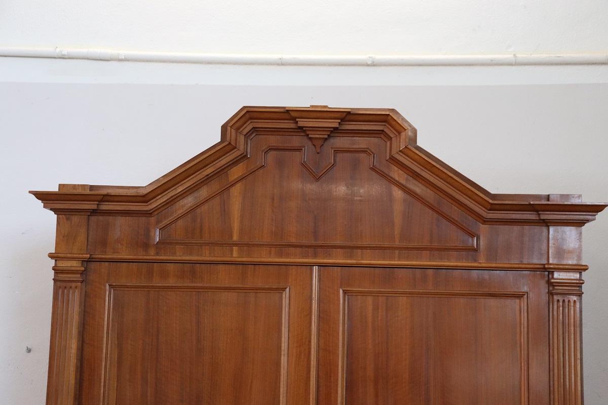 Antique italian wardrobe in walnut veneer wood made in late 19th century. Very particular wardrobe characterized by a slender upper part with a geometric line frame. Equipped with two doors, the interior is equipped with a rod for hanging clothes,