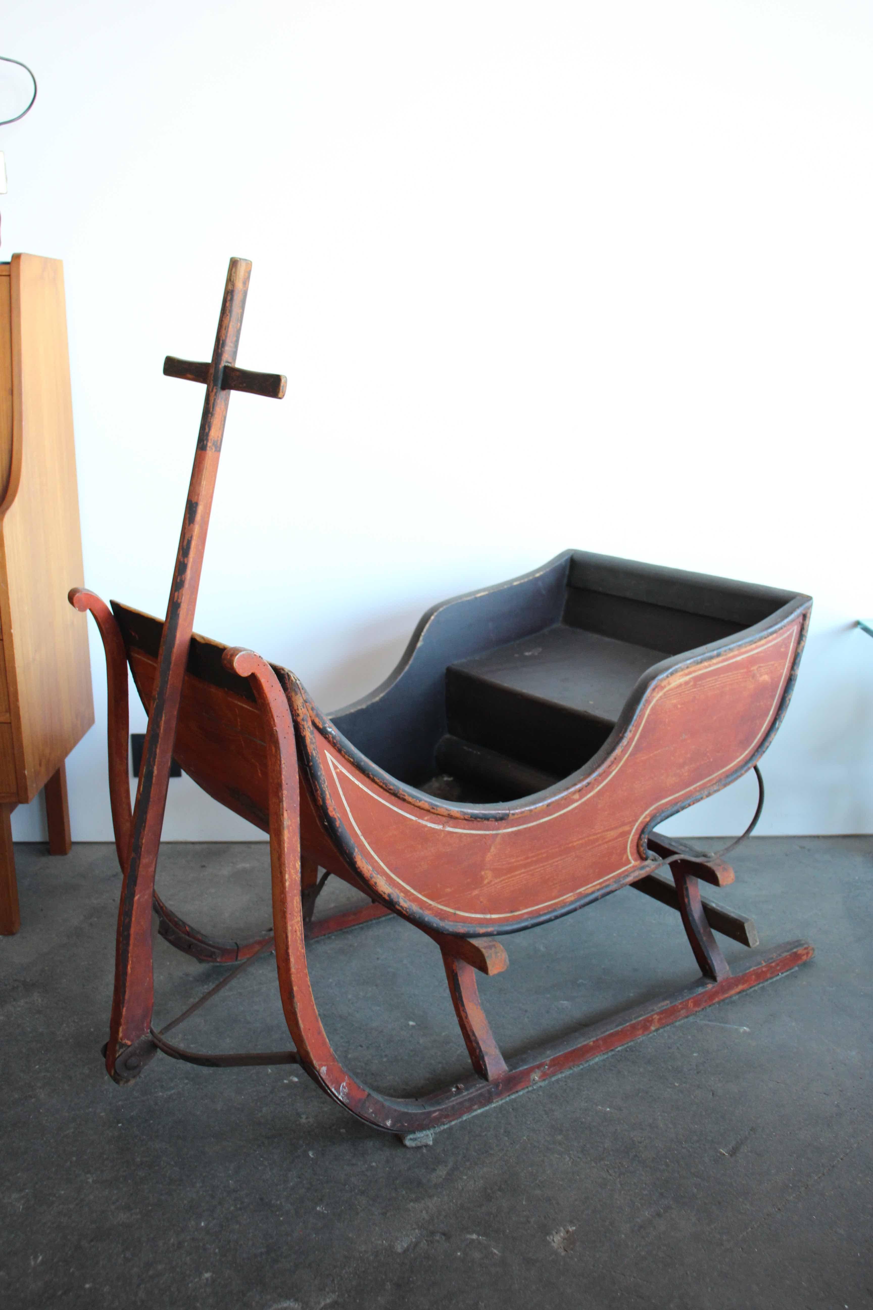 This rare antique sledge still has the original painting from the 19th century. From the outside it is painted in a beautiful rust red and has a golden yellow decorative line, from the inside everything is black. The complete sledge is made of wood