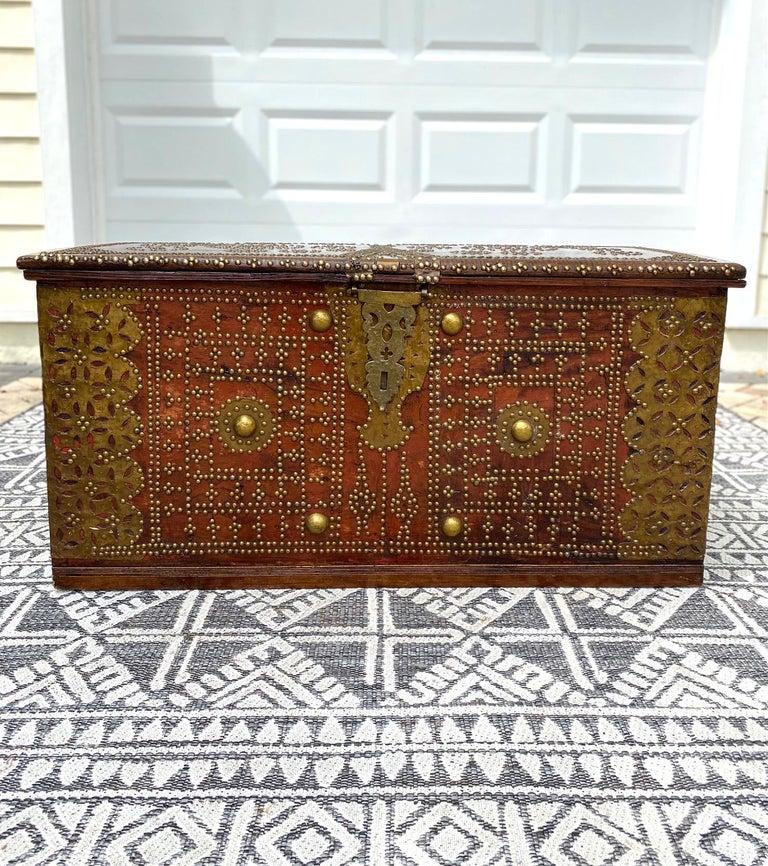 Rare 19th century handcrafted Zanzibar chest with brass metal overlay and brass mounts. The antique trunk is comprised of solid carved teak and hardwood and features ornamental hinged lid. The interior is fitted with a candle box on the upper right