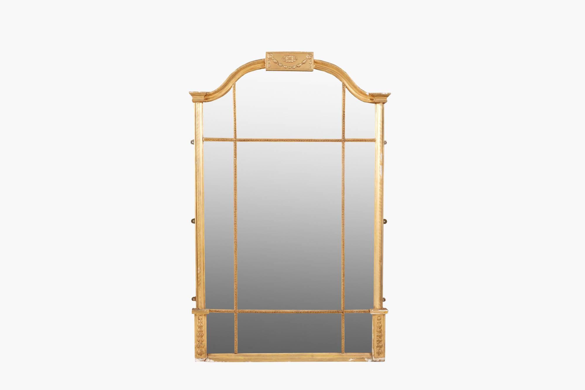 19th Century arch-top pier mirror in the style of Adams, with delicate cock-beaded moldings separating nine mirror panels. The giltwood frame has a carved central crest with floral swag ornamentation. The pillared sides terminate in ornamental