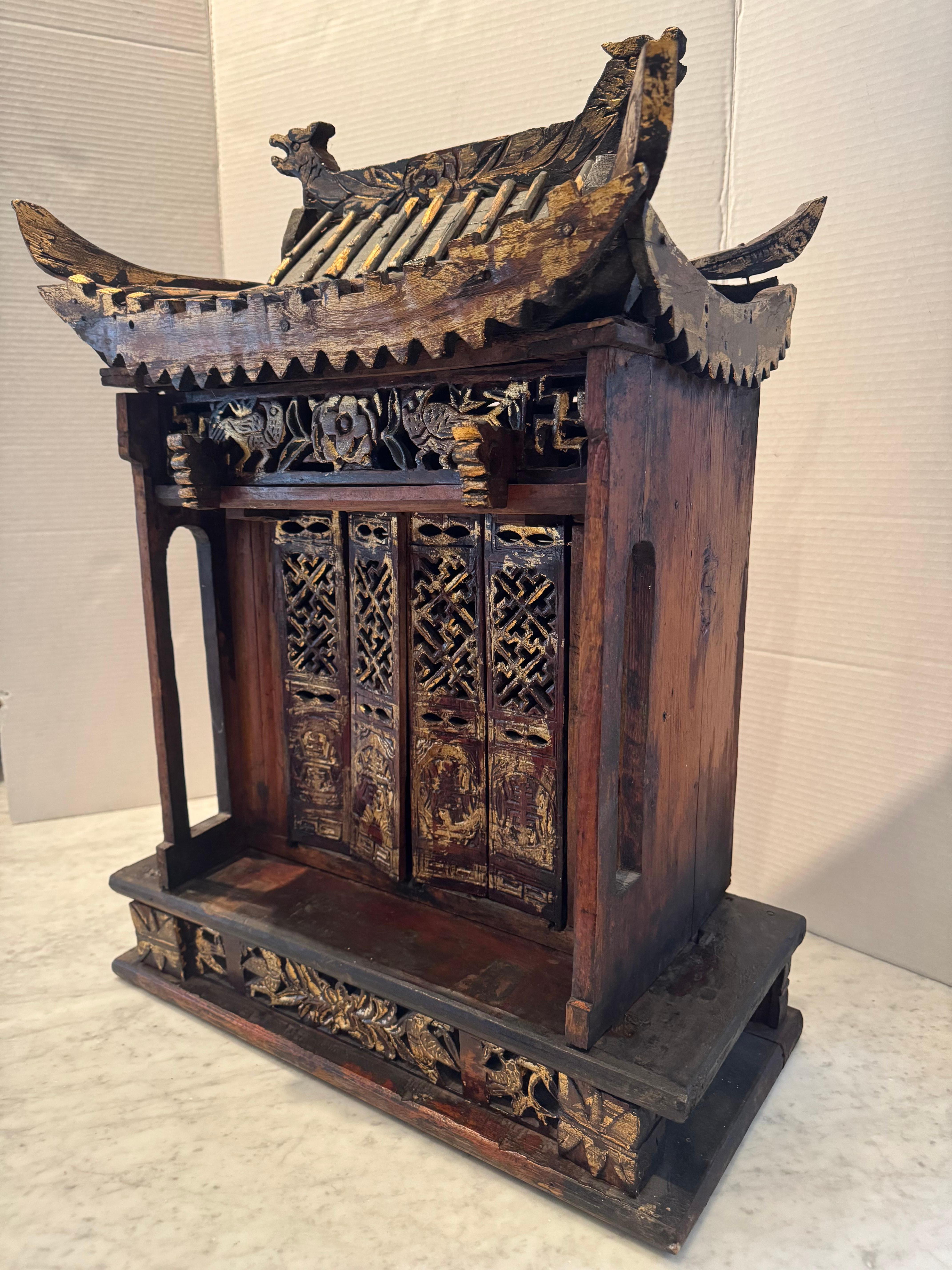 La maquette architecturale d'un temple chinois, méticuleusement sculptée et dorée, constitue une œuvre d'art fascinante.