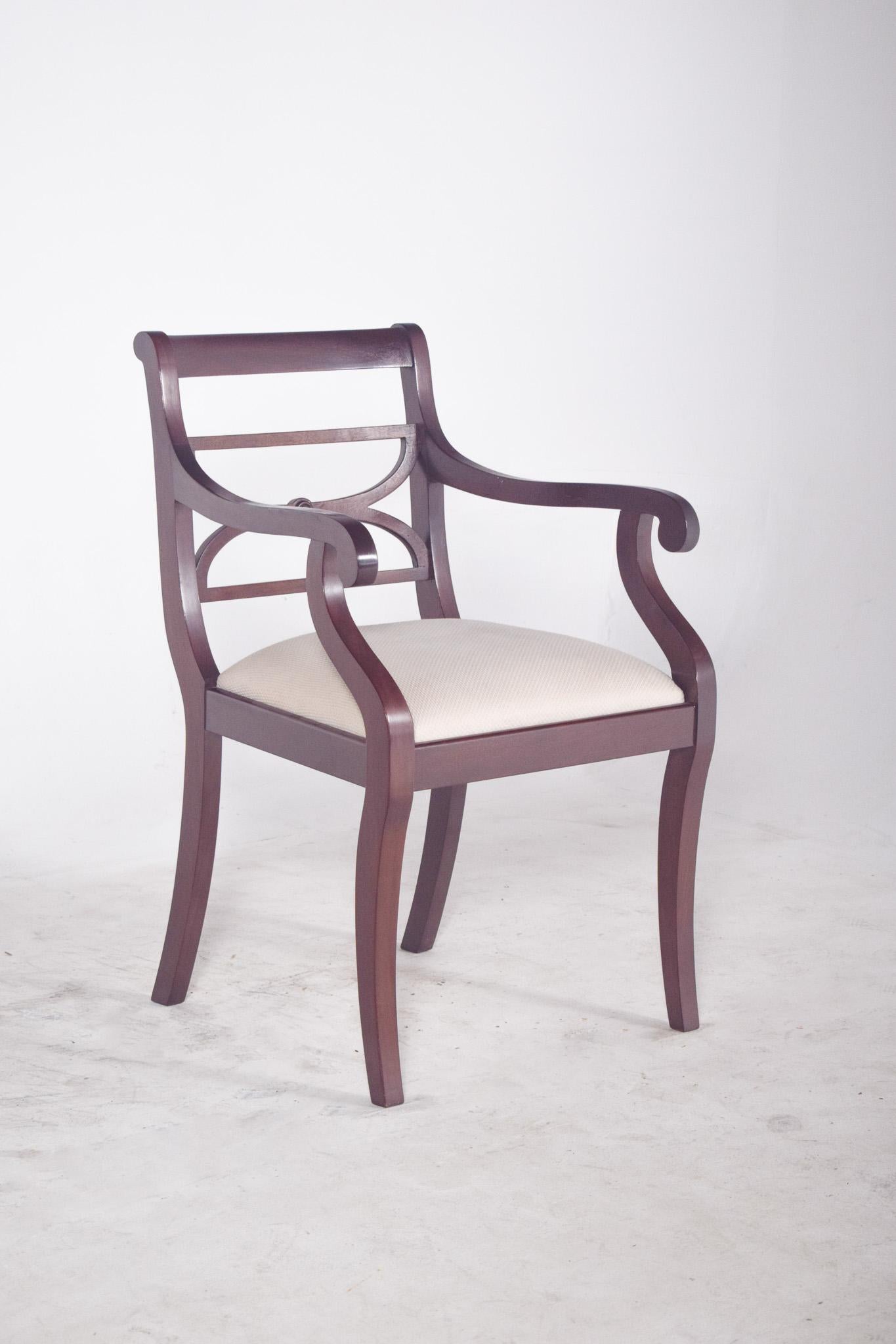 Sillón con asiento tapizado en beige. Esta silla combina elegancia clásica y sencillez. La estructura de madera oscura tiene un acabado pulido y formas suavemente curvadas en los brazos, que proporcionan comodidad y una estética fluida. El respaldo