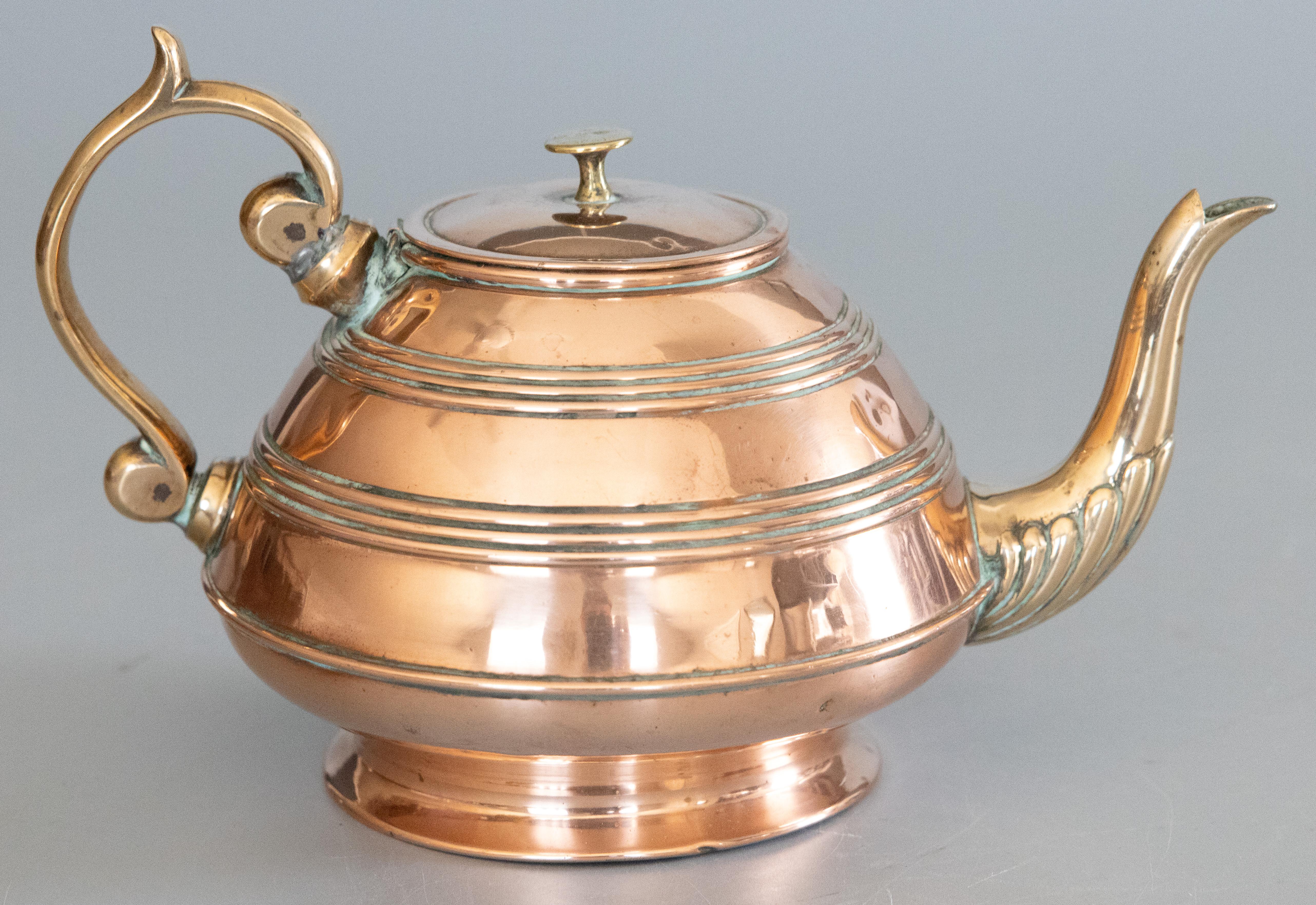 A lovely antique Art Nouveau style English copper and brass tea kettle or teapot by Soutter & Sons, circa 1890. This fine tea pot has a handmade copper body with brass handle and spout in a lovely patina. It would a charming addition to your kitchen
