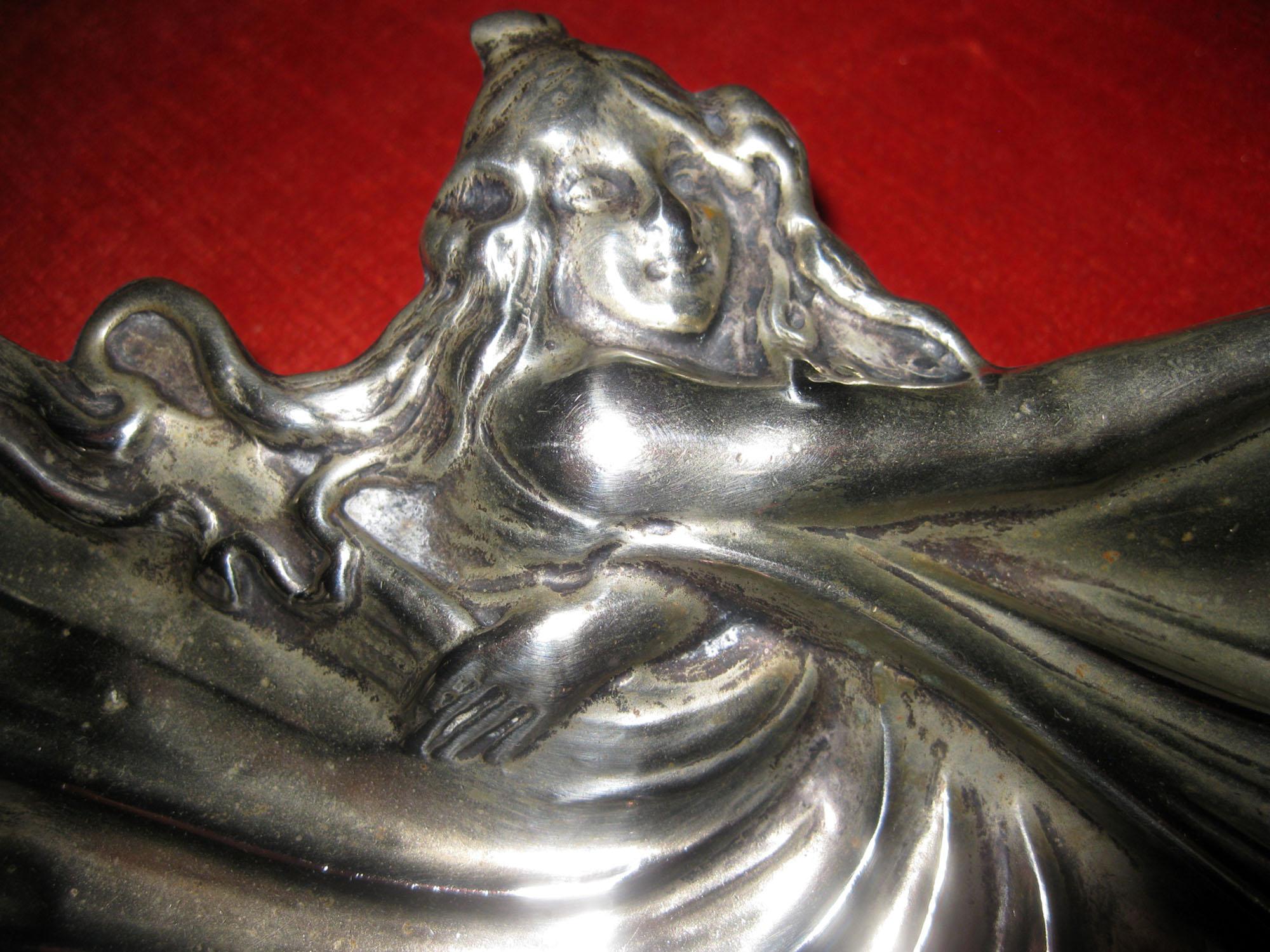 This small interesting Art Nouveau silver footed tray depicts a long-haired maiden swirling her dress in the shape of butterfly wings. It rests on three round feet. It is hallmarked Meneses which is a Spanish silversmith founded in 1840 and has been
