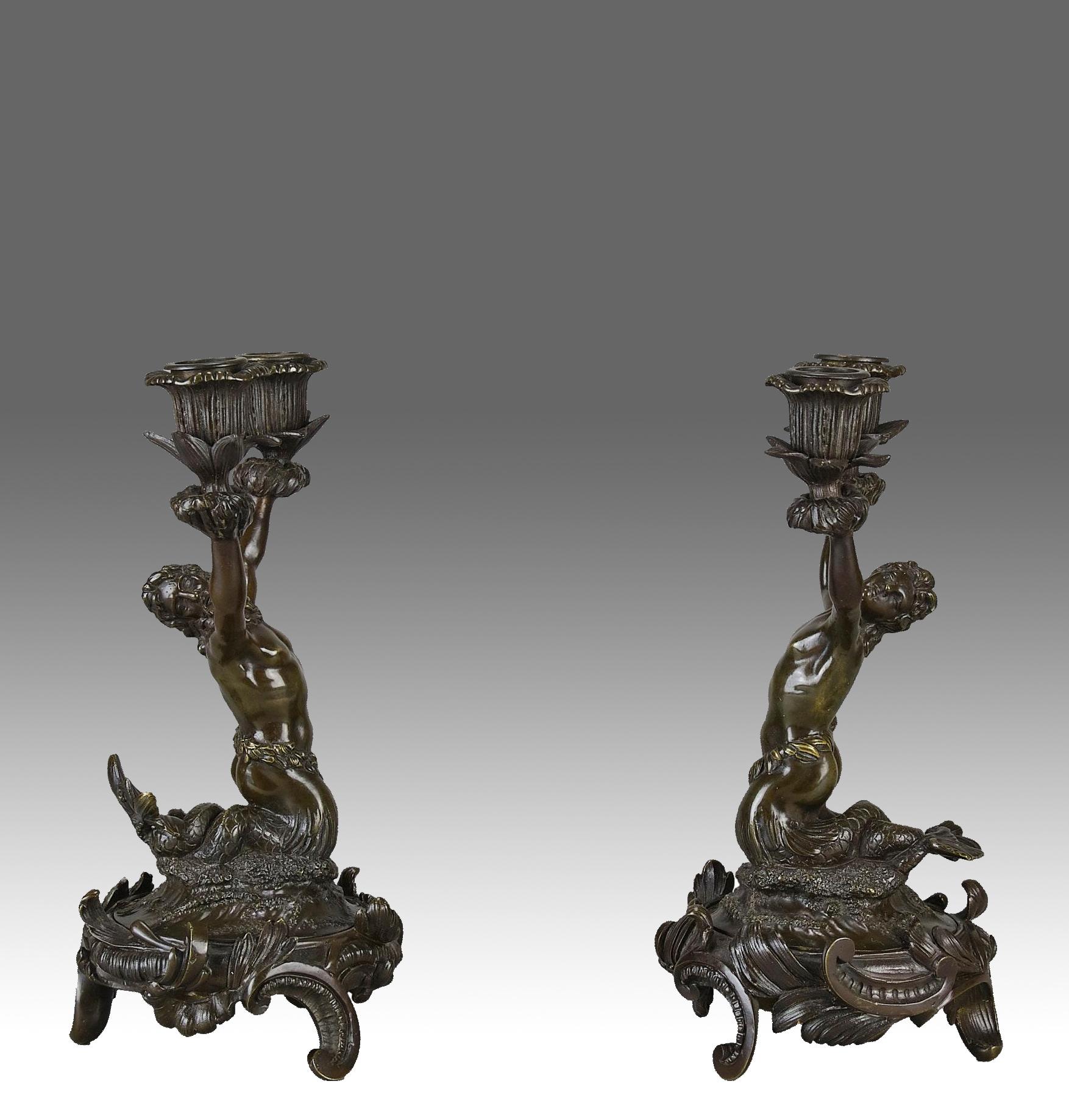 Pareja muy decorativa de candelabros de bronce de finales del siglo XIX con dos sirenas arrodilladas sobre trípodes de bronce ornamentalmente decorados que sostienen los candelabros, con excelentes detalles de superficie cincelada a mano y una