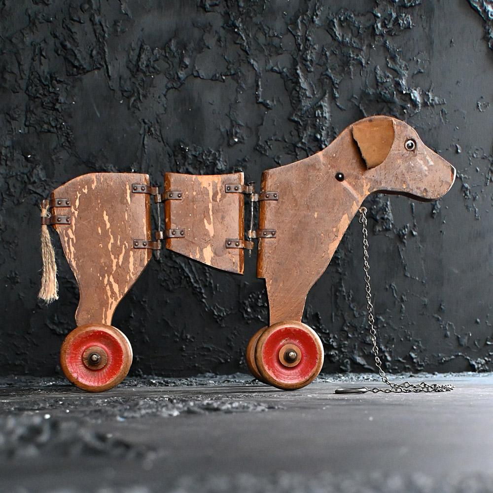 19th century articulated pull along dog toy 
A wonderful example of a late 19th Century articulated pull along dog, constructed from pine and metal hinged body with painted detail surface. Original fabric canvas ears still intact as is its full