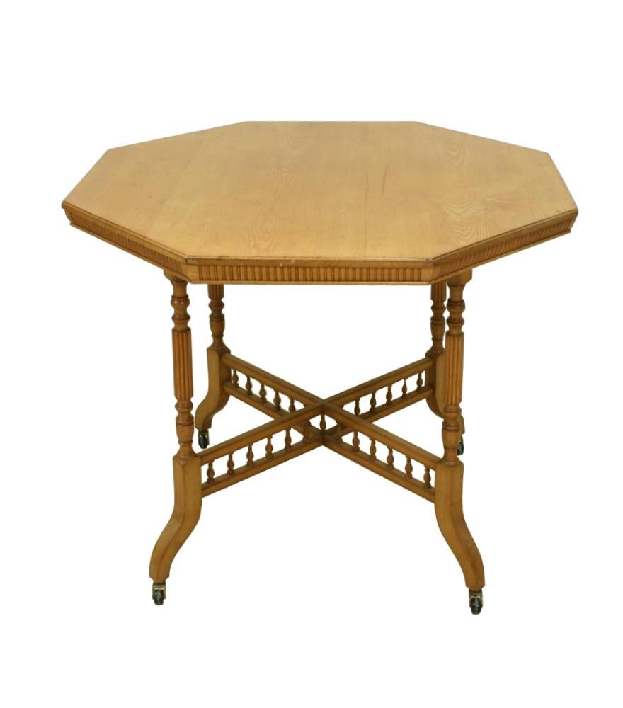 A very attractive blonde oak centre table by James Shoolbred. The table is raised on turned and fluted legs, united by an X-framed stretcher with bobbin turned decoration, the table edge is also carved. The underside of the table has a plaque with