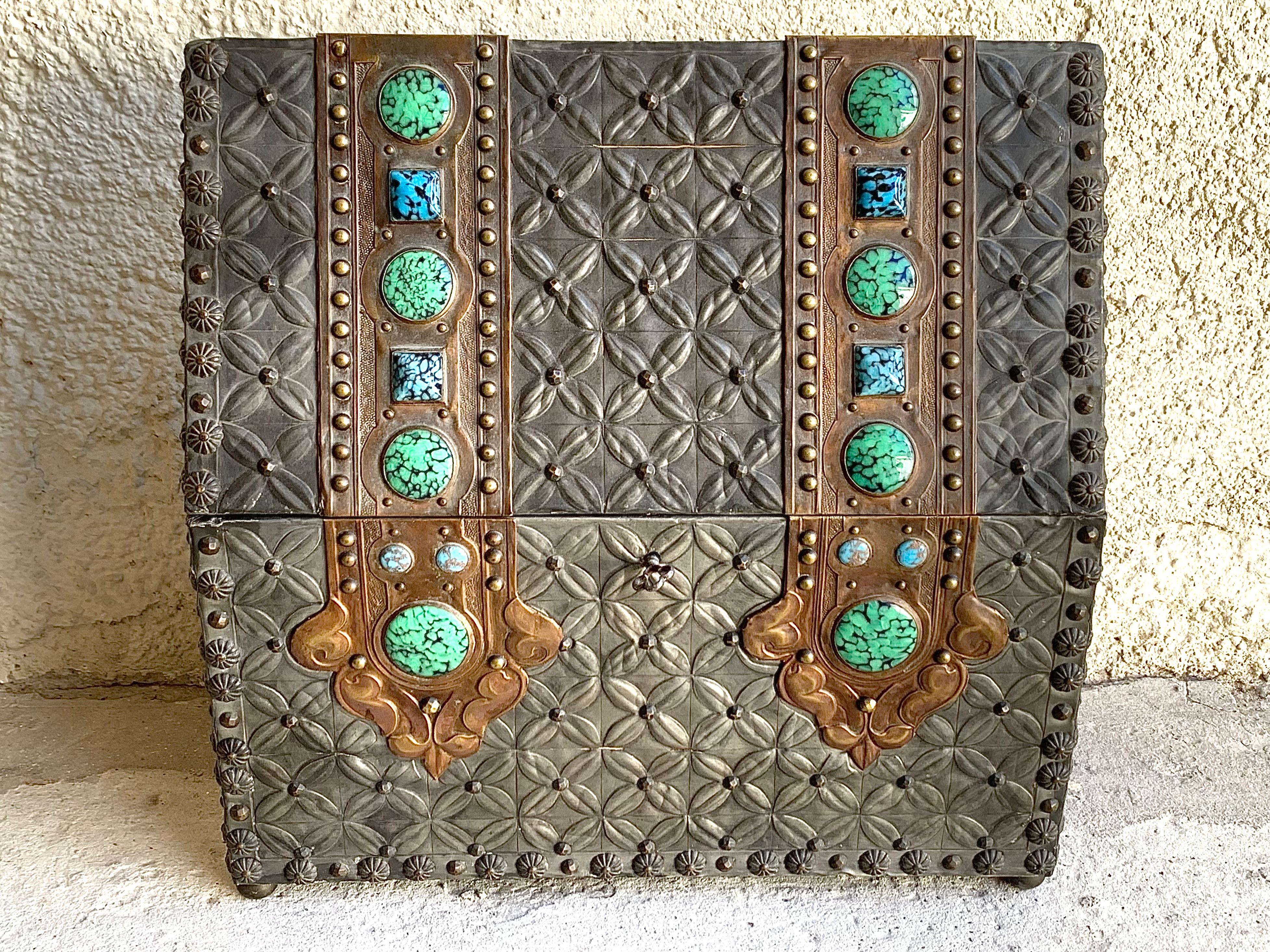 It was a great pleasure to find this rare Arts & Crafts pewter and copper box.
The copper applications are decorated with green and blue glas cabochons.
The wooden carcass is covered entirely with pewter, embossed with quatrefoils. The edges of the