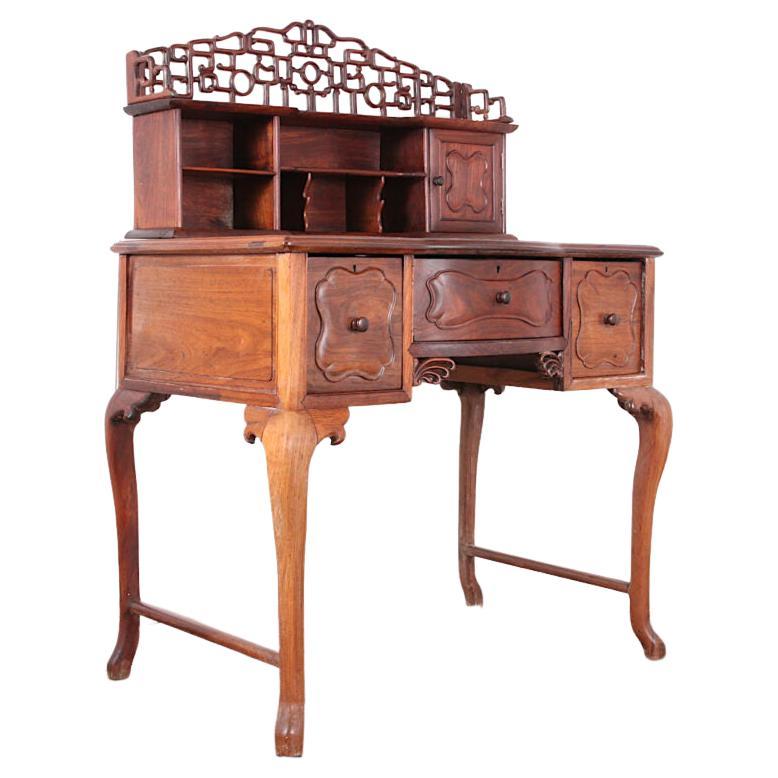 A late-19th century carved Chinese hardwood writing desk with three lower drawers and an upper-back superstructure with pierce-carved gallery, shelving and a small cabinet. A pretty smaller-scaled desk in excellent original condition. C.