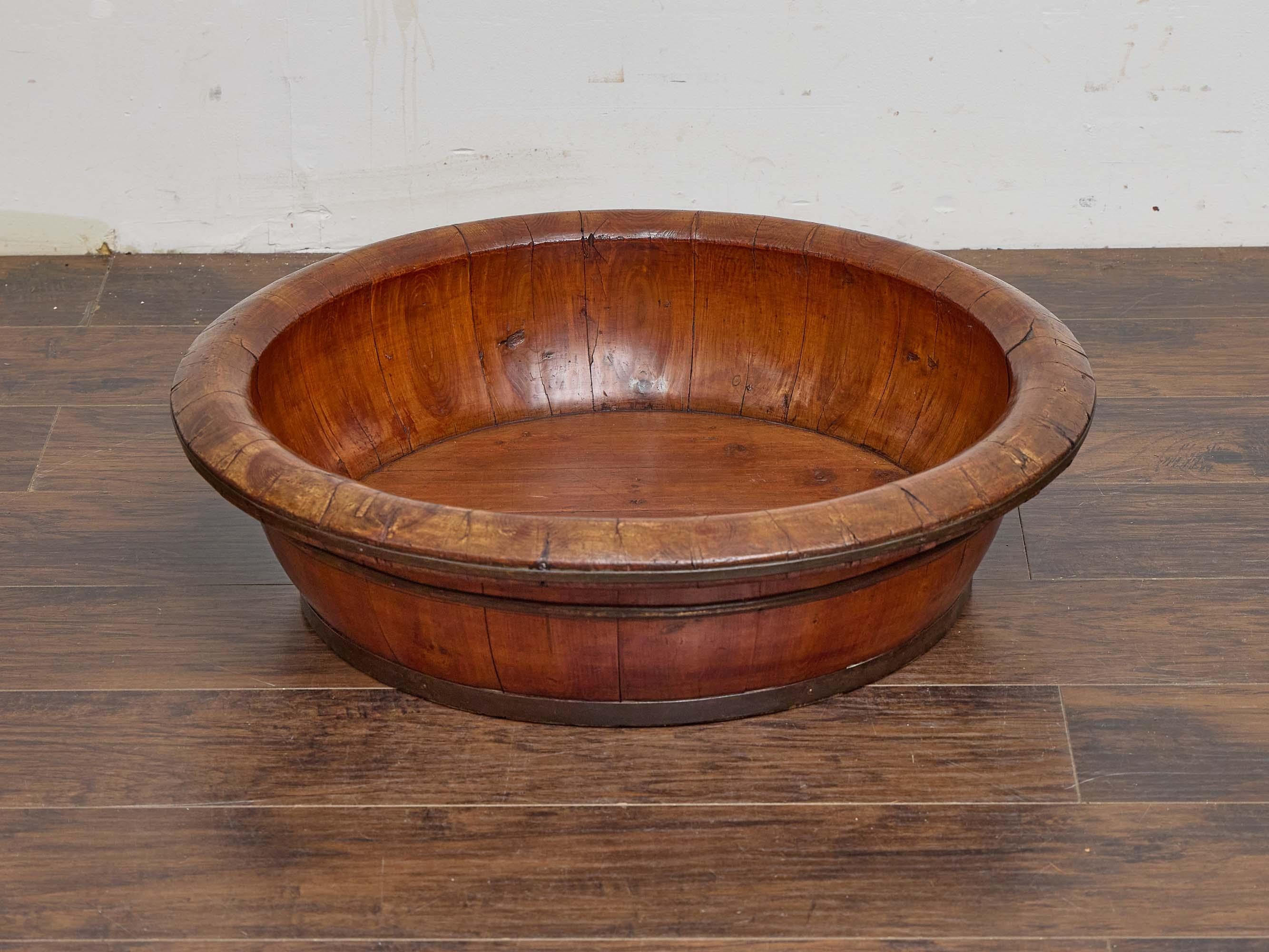 Gran cuenco asiático de madera dura del siglo XIX, fabricado mediante técnicas tradicionales de tonelería con anchas duelas unidas por bandas de latón. Con un diámetro de 29 pulgadas y una altura de 10,5 pulgadas, el recipiente presenta un borde