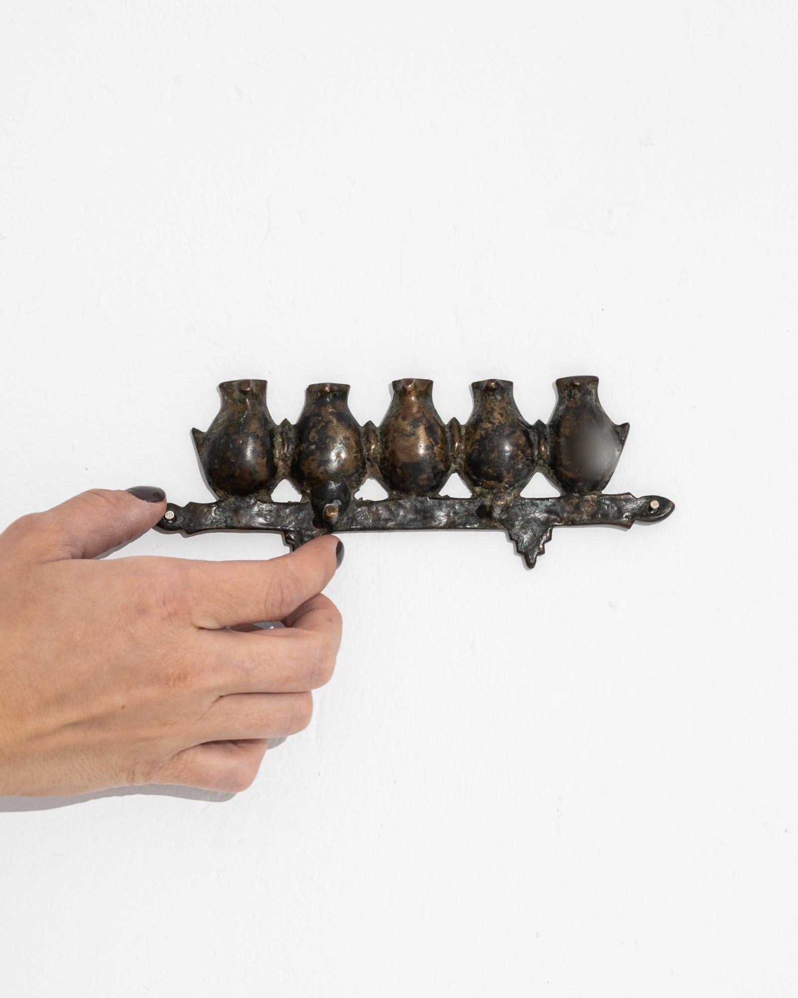 A 19th century bronze wall decoration produced in Asia, this unique piece presents a row of five plump birds standing on a stylized branch, completed by two little hooks. Flaunting a lush oxidized patina, the bronze displays a rich palette of jet