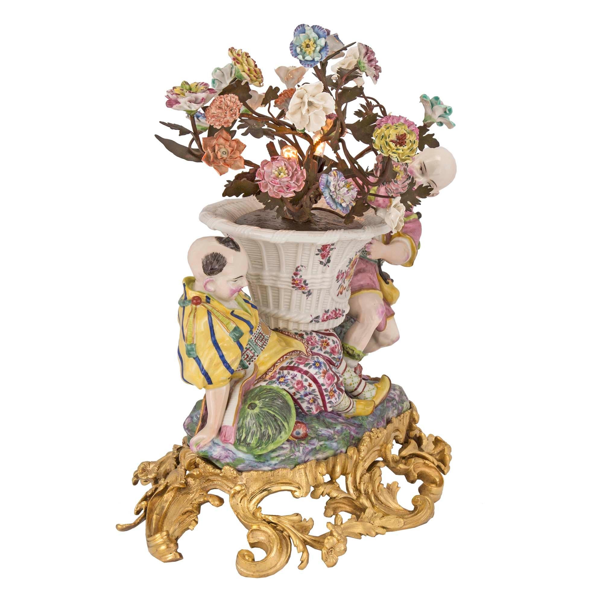 A lovely 19th century Asian export decorative lighted porcelain with French Louis XV st. ormolu base. The pierced finely chased base has wonderfully scrolled foliate all around. The charming porcelain figures above are in traditional attire, with