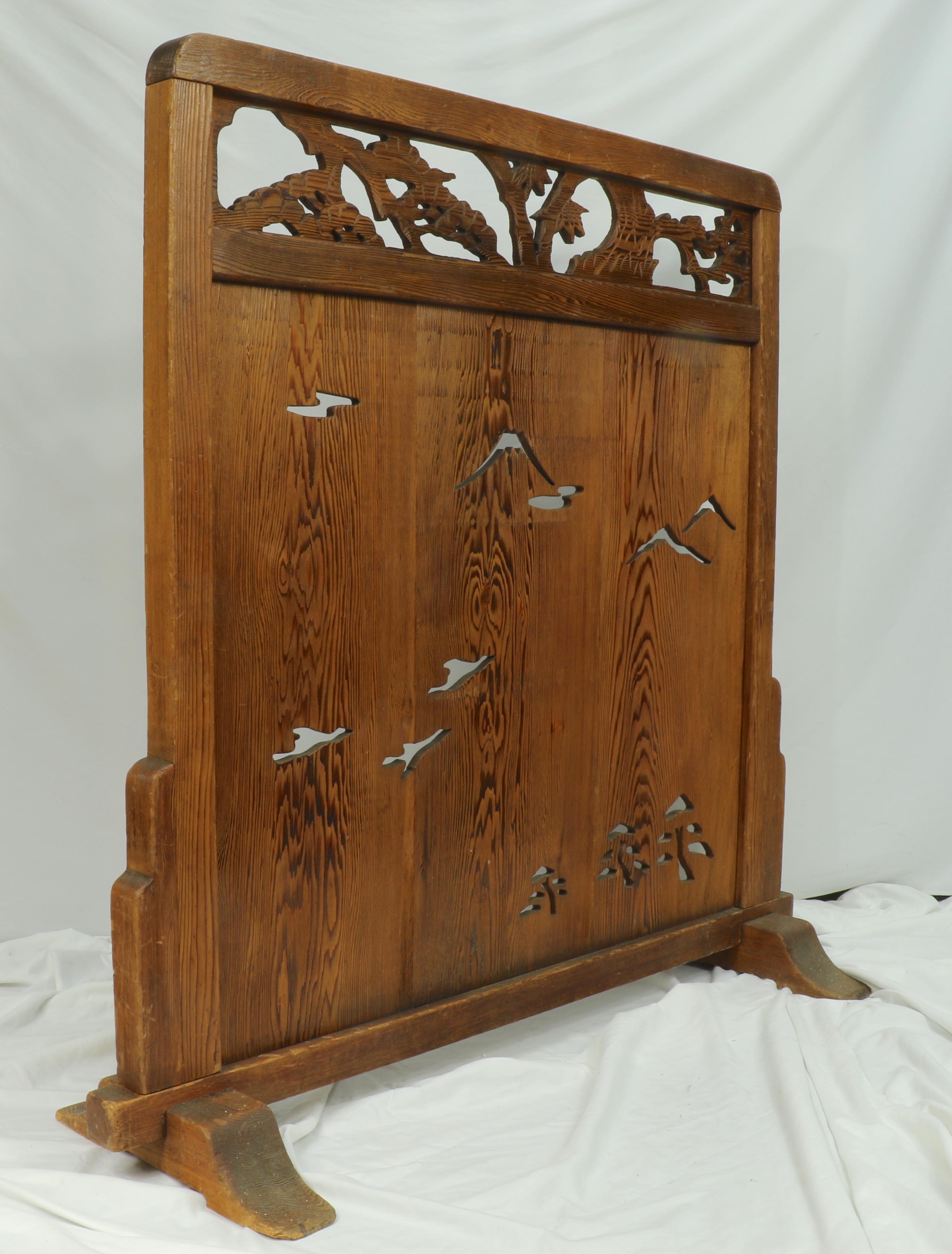 The delicate open hand-carving on this screen is distinctive. This is a late 19th, early 20th century Chinese divider screen made from hand-carved redwood and motifs that include mountains, trees and birds in flight. 
This rectangular divider rests