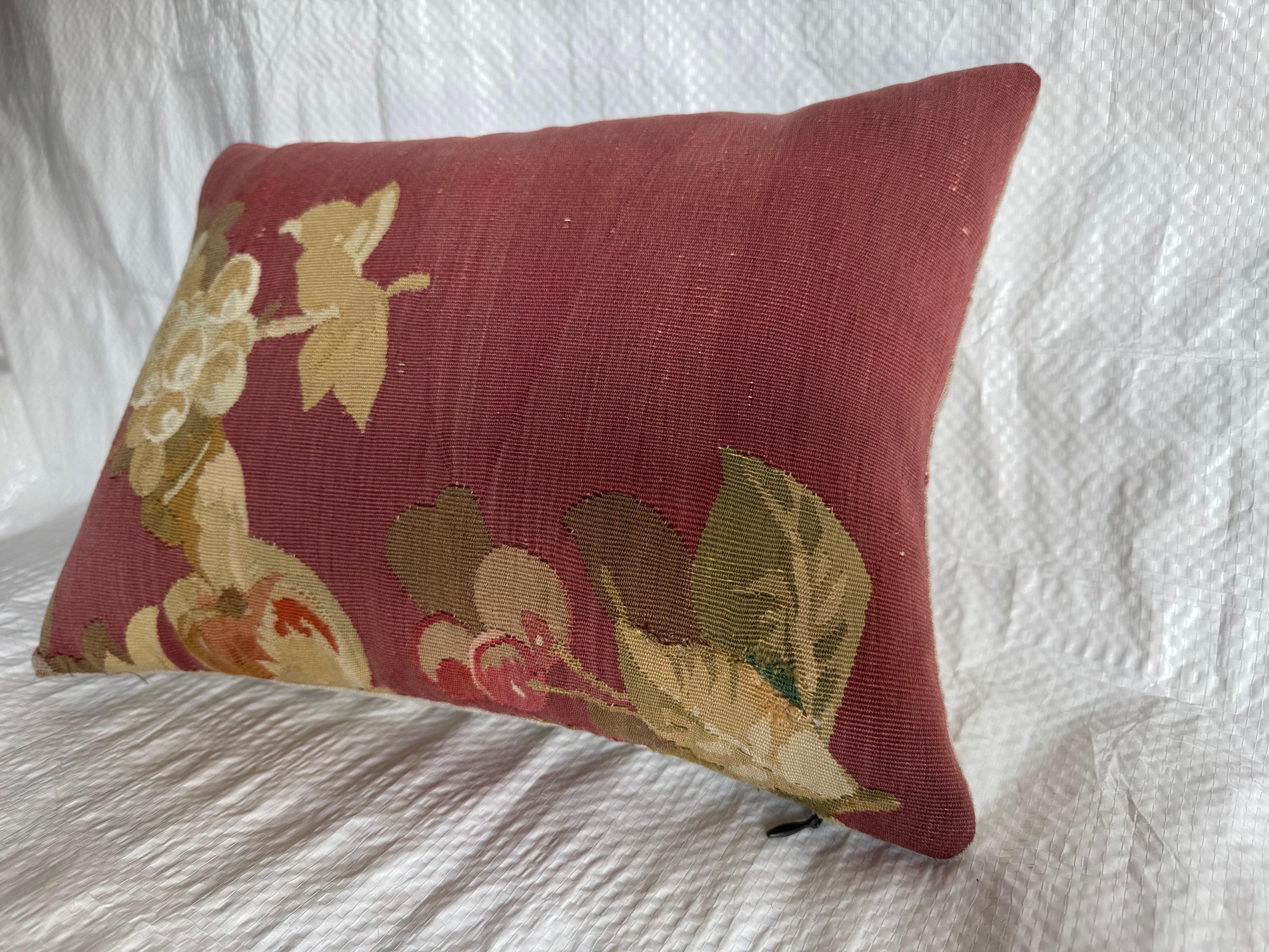 Ce coussin est fabriqué à partir d'un fragment de tapisserie d'Aubusson du milieu du XIXe siècle, datant d'environ 1850. L'imagerie met en évidence des grappes de raisin et de fruits avec des feuilles, tissées dans des tons doux d'ivoire, d'ocre et