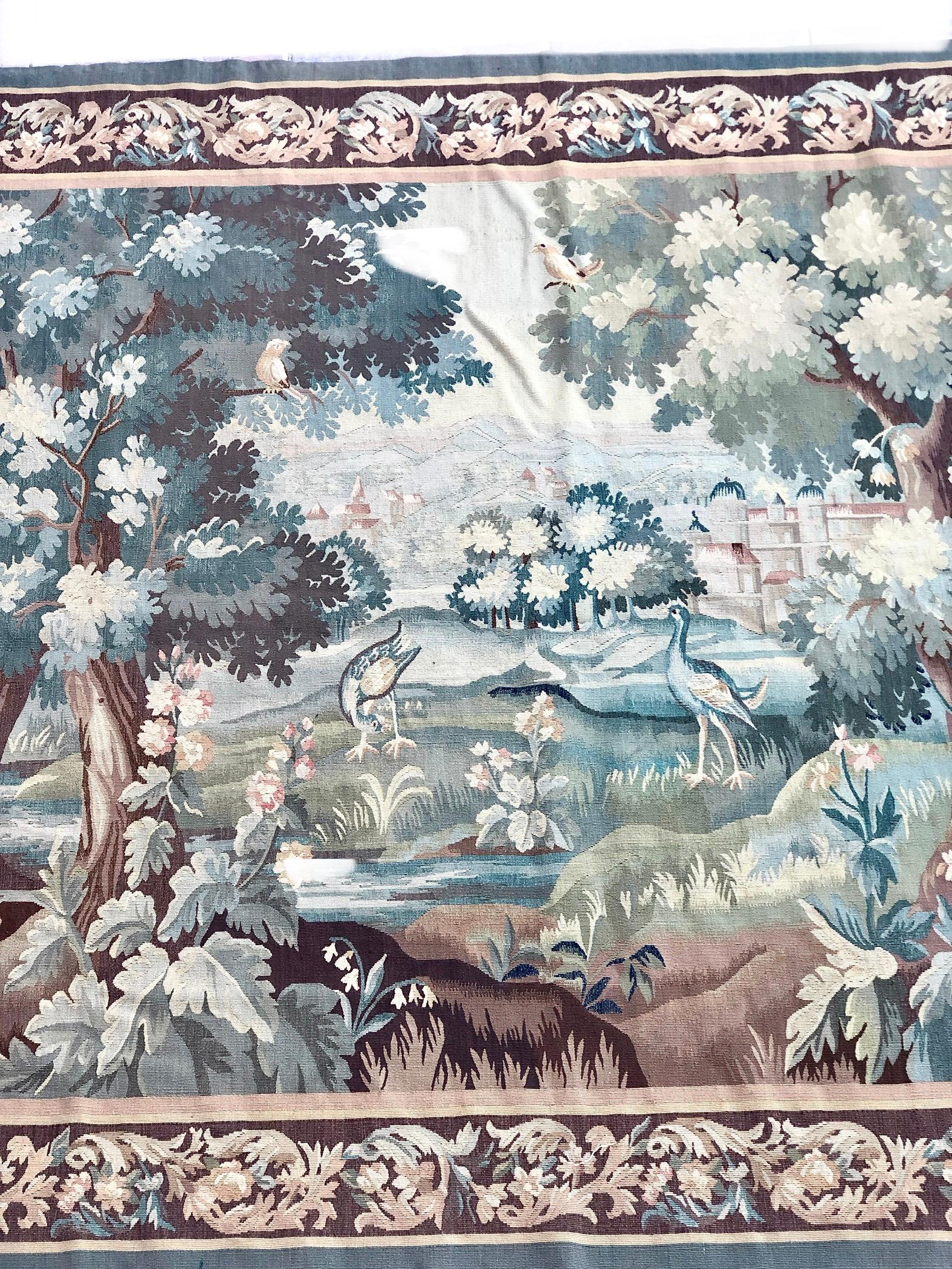 A particularly fine 19th century Aubusson Verdure tapestry, depicting a landscape scene of the French countryside, with a castle in the background, a village hiedden behind the trees and birds foraging amidst the lush foliage next to a trickling