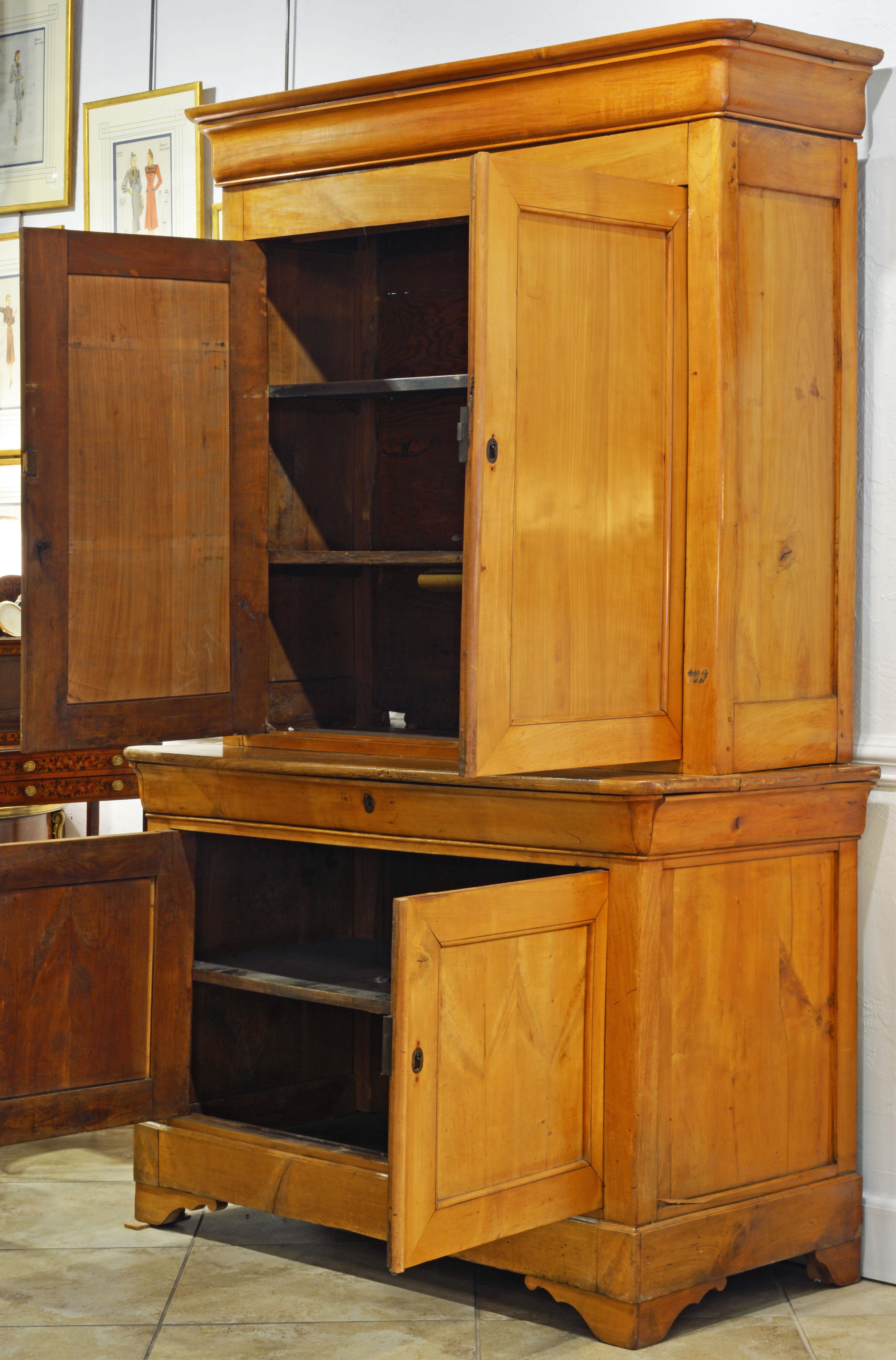 This honey colored Austrian fruit wood step back cupboard features an upper section with two doors opening up to a shelved interior and a slightly bigger lower section with a long frieze drawer, two doors and one shelf. It is topped by a molded