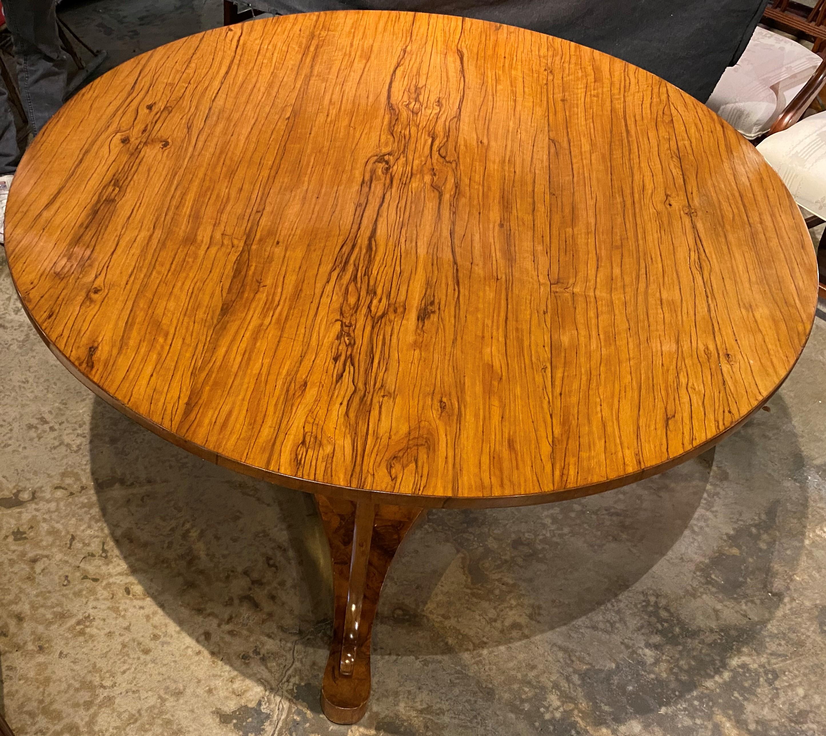 A fine Biedermeier fruitwood round center table with spectacular veneers, supported by a center pedestal with tripod cabriole legs attached to a triangular base stretcher. The table is Austrian in origin, dating to the 19th century, in very good
